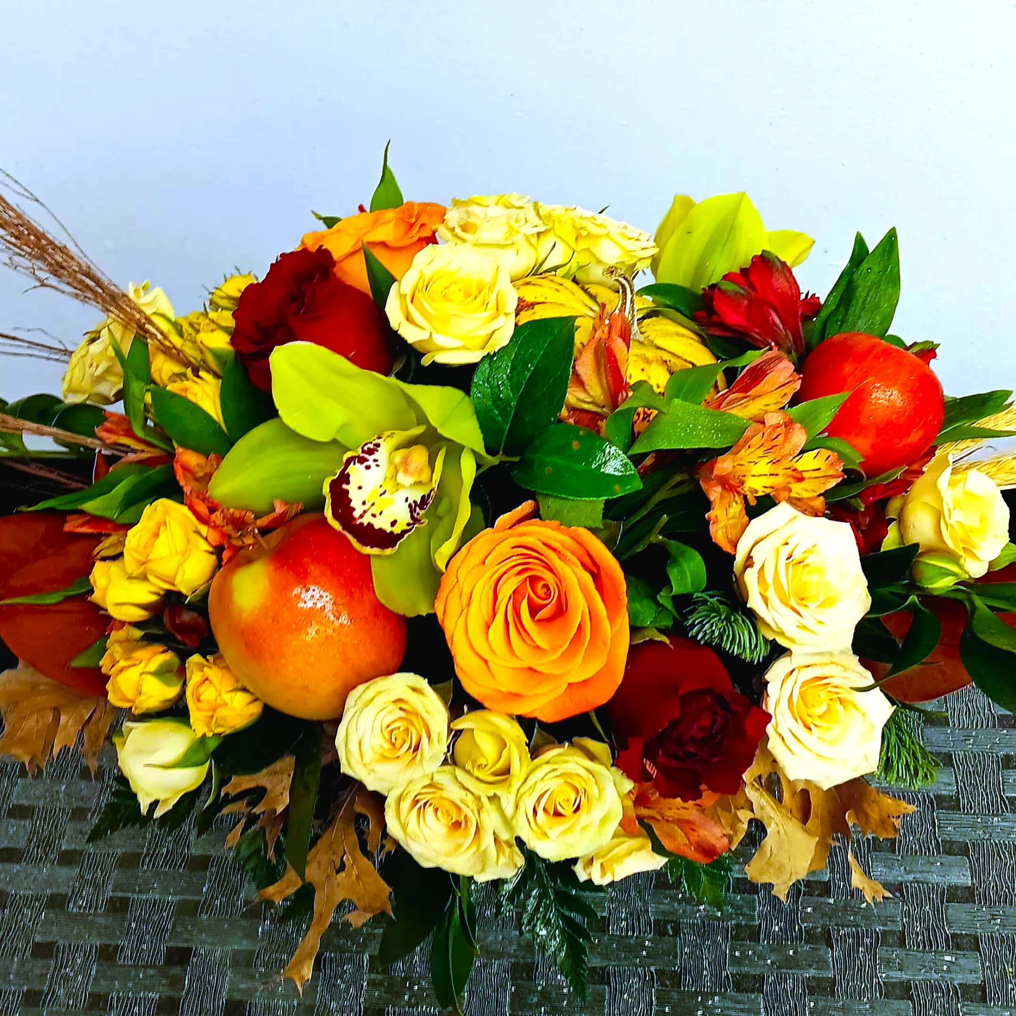 Mixed bouquet of roses and orchids with fruit accents