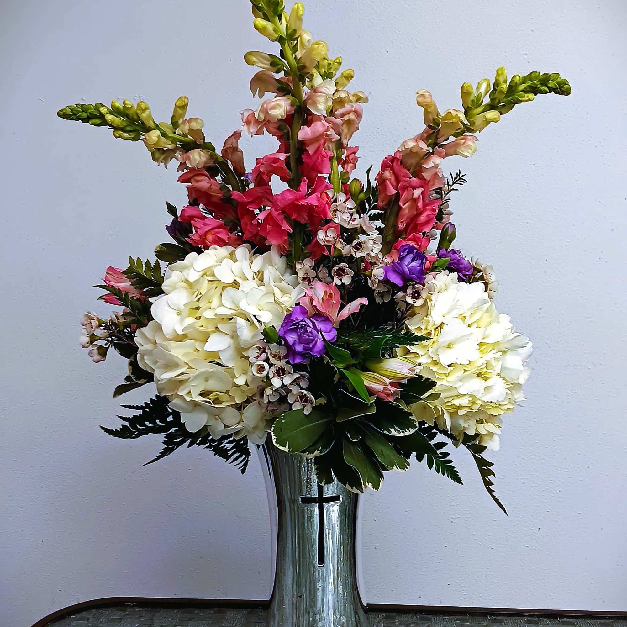 Tall floral arrangement in a silver vase with white, pink, and purple blooms
