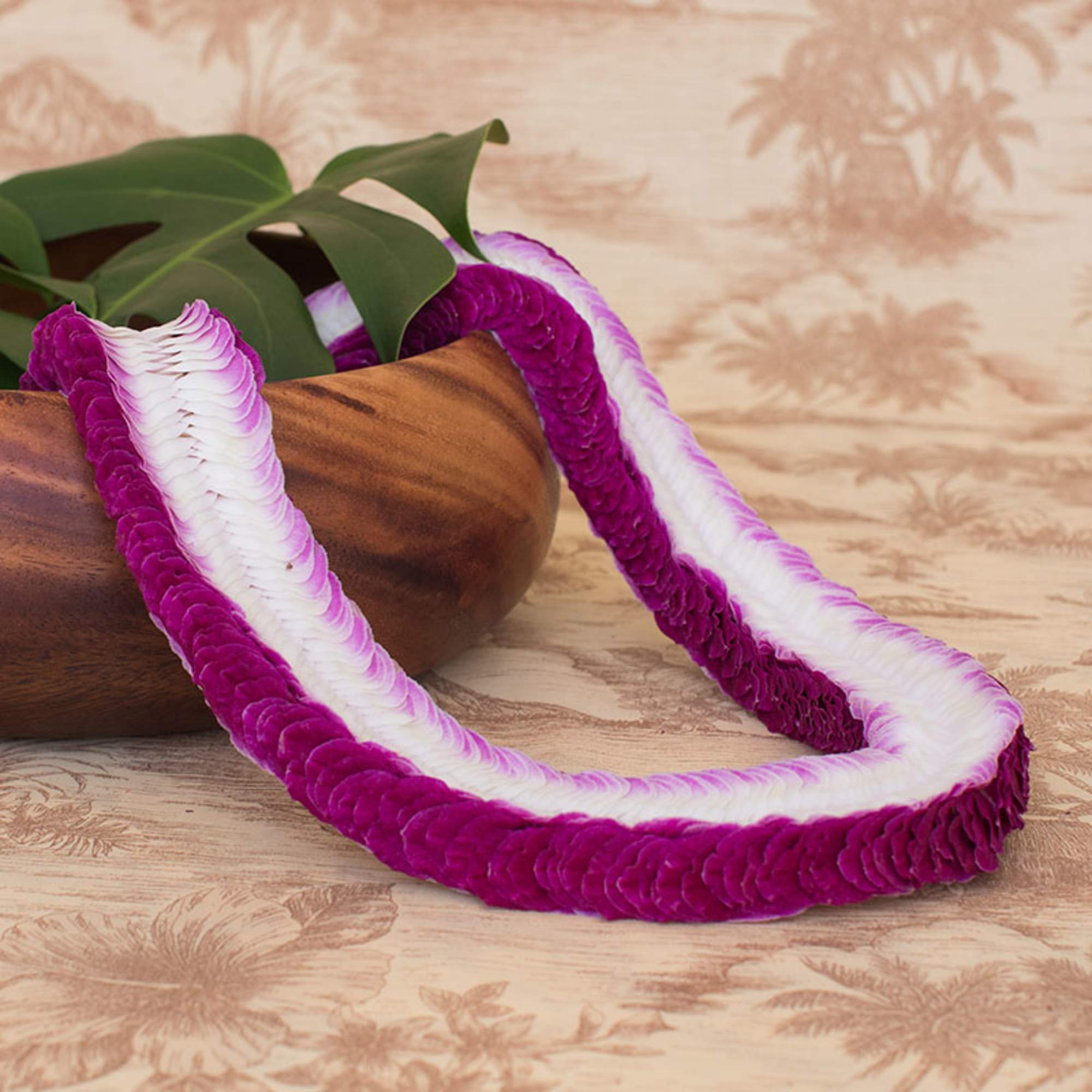 Purple and white flower lei draped over a wooden bowl