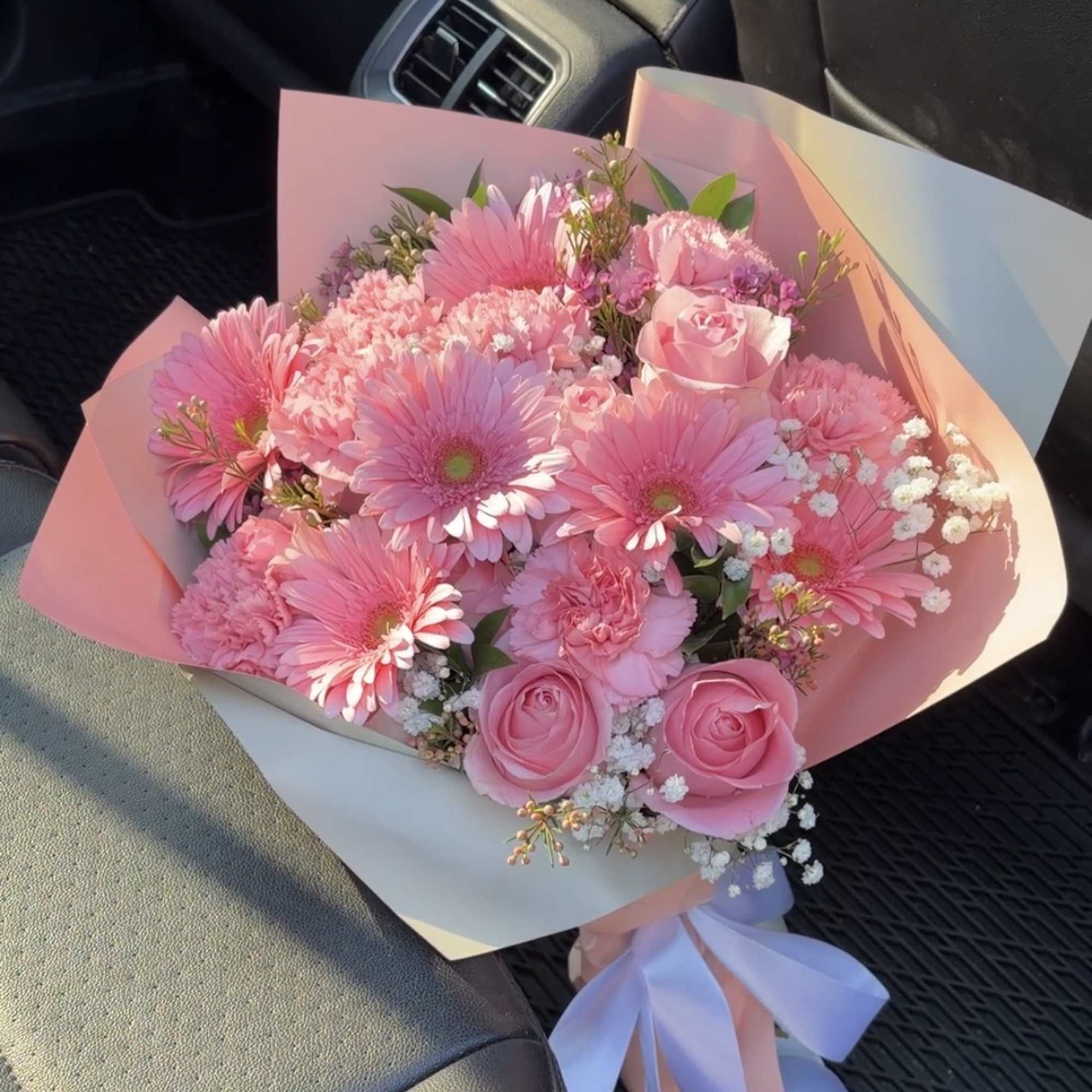 Pink bouquet with gerbera daisies, roses, and carnations wrapped in pastel paper