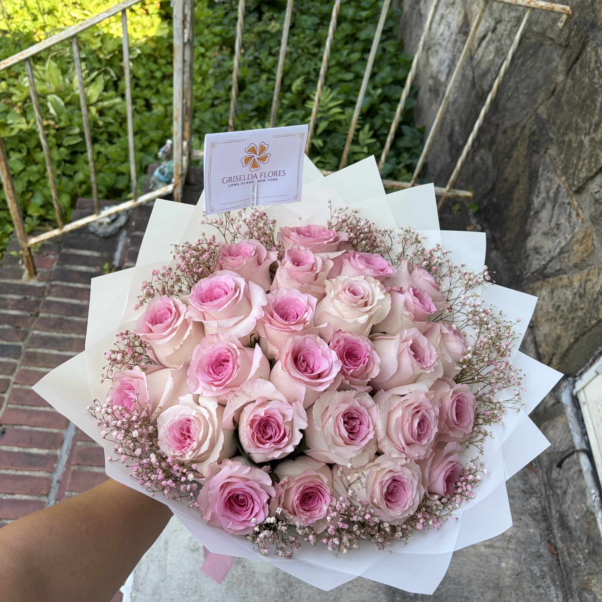 Bouquet of pink roses with baby's breath in white wrap
