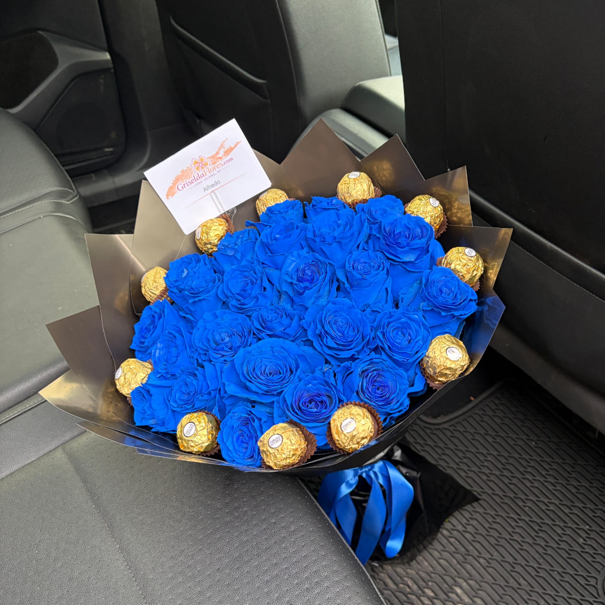 Bouquet of bright blue roses with gold-wrapped chocolates in black paper