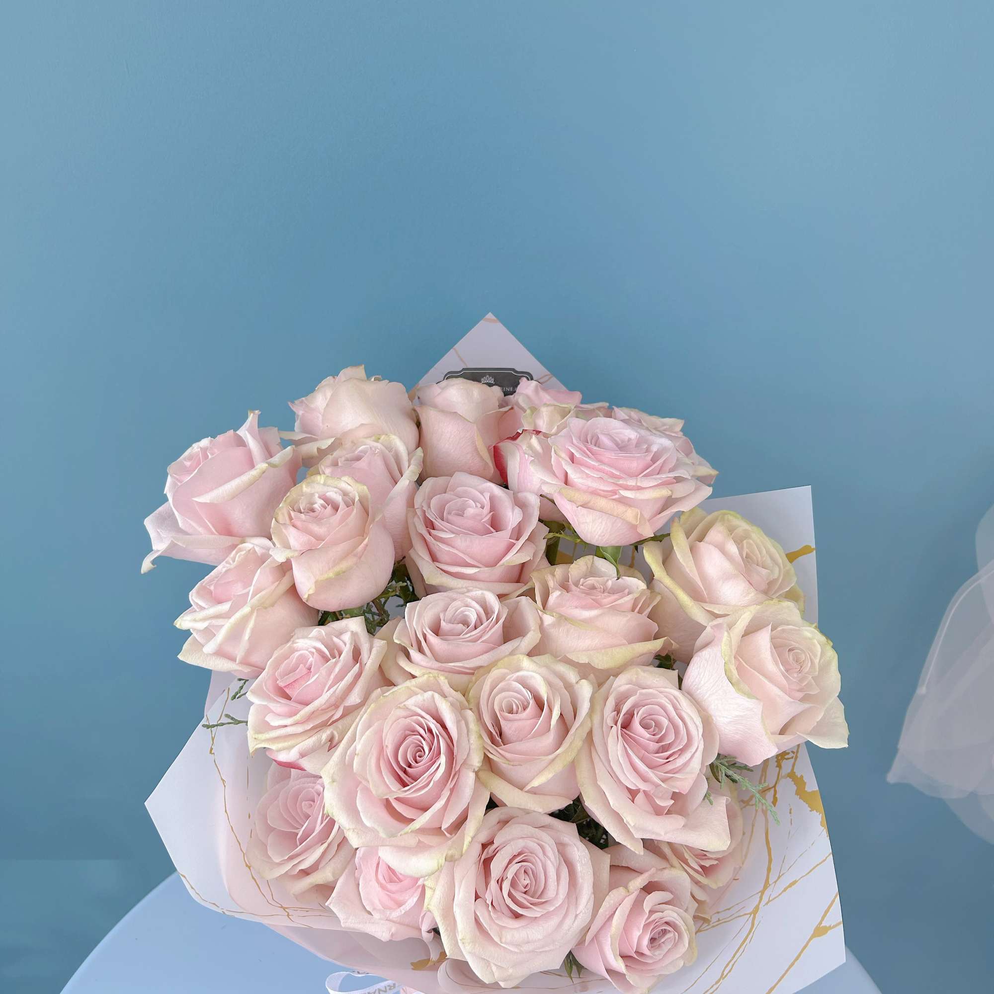 Bouquet of pale pink roses wrapped in white paper
