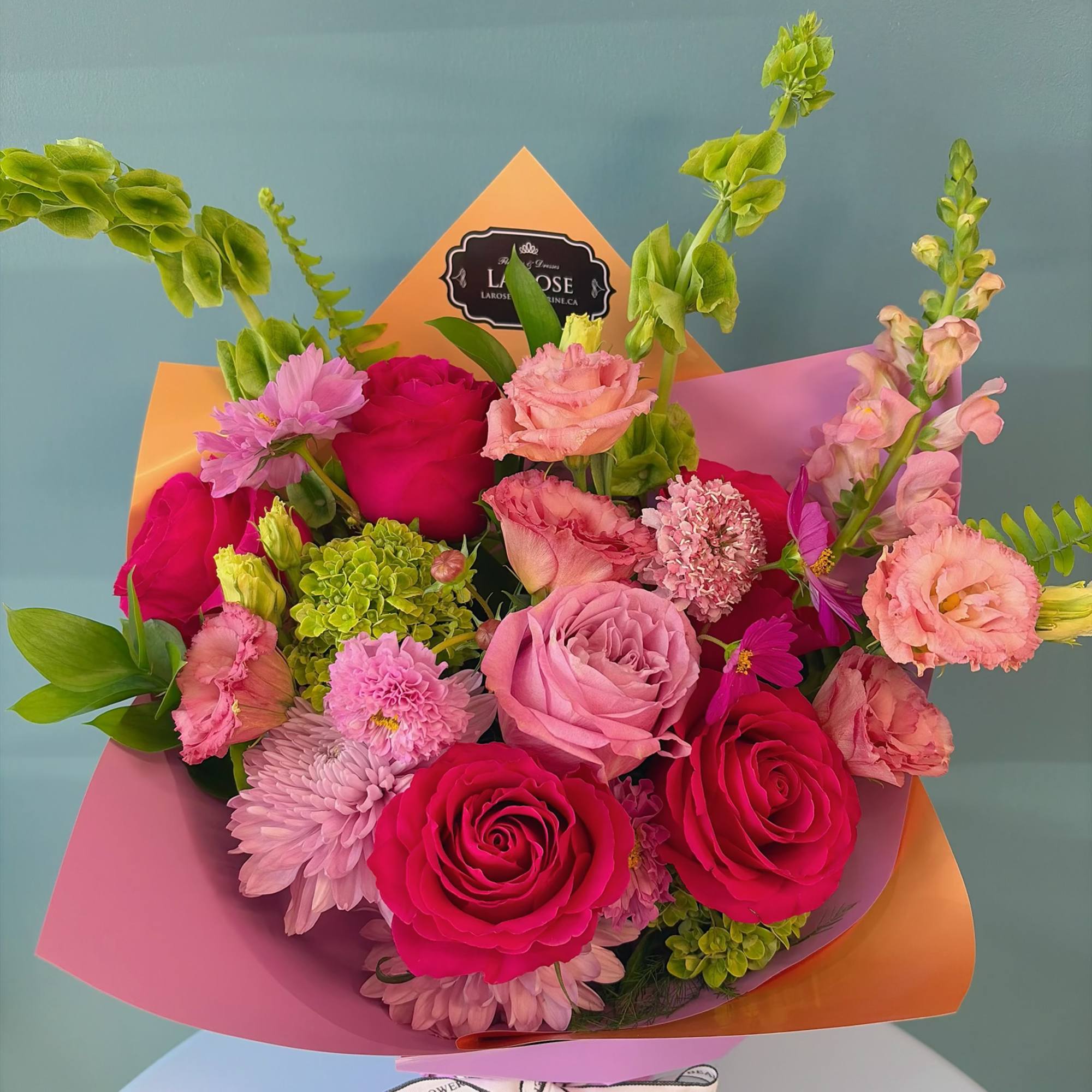 Bouquet of pink and magenta roses with mixed blooms in pastel wrapping