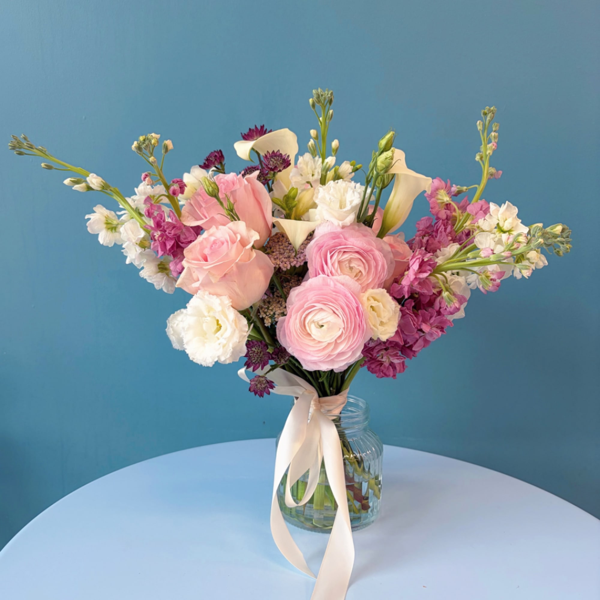 Pink and white wedding bouquet in a glass jar with a ribbon