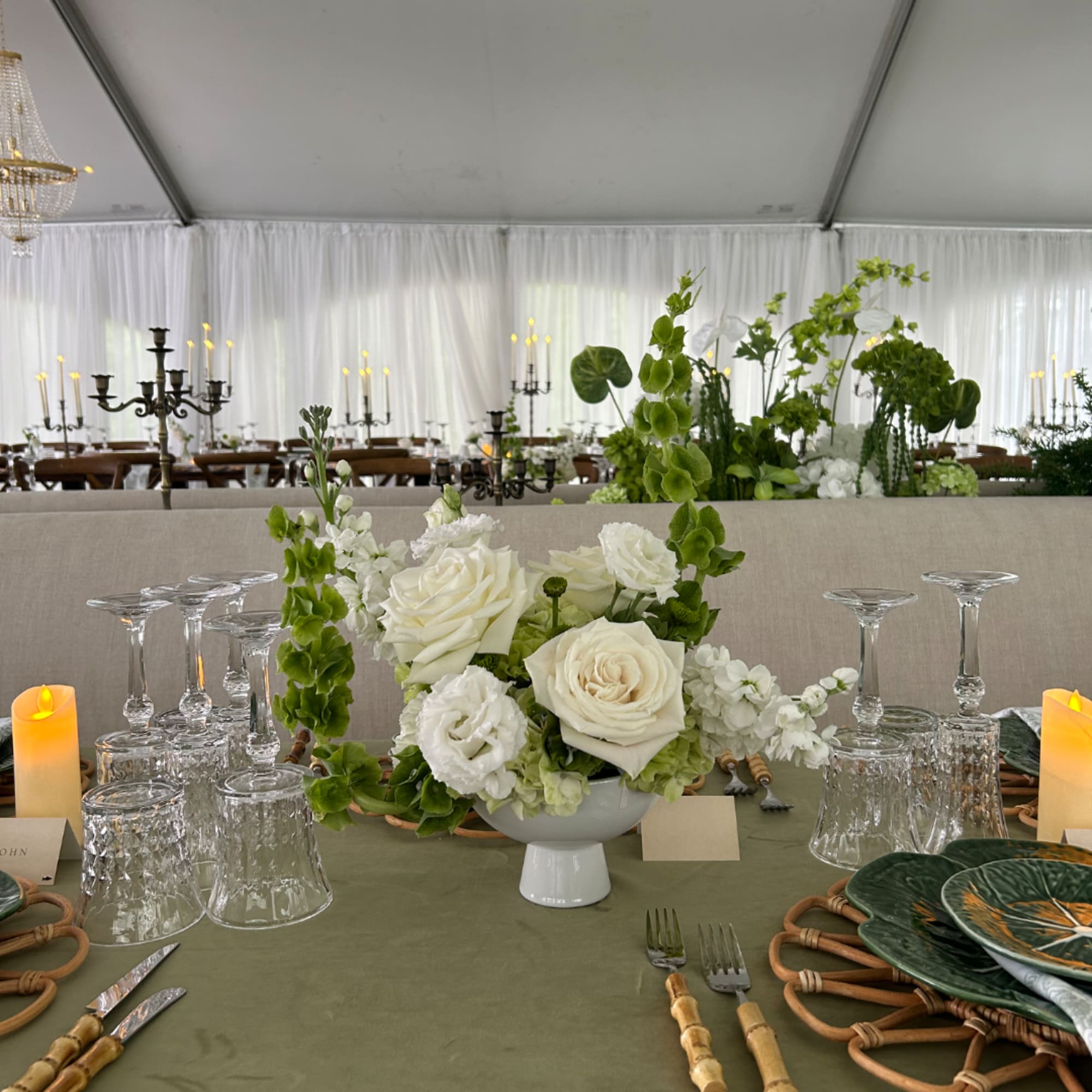 White rose centerpiece in a white pedestal bowl on a decorated table