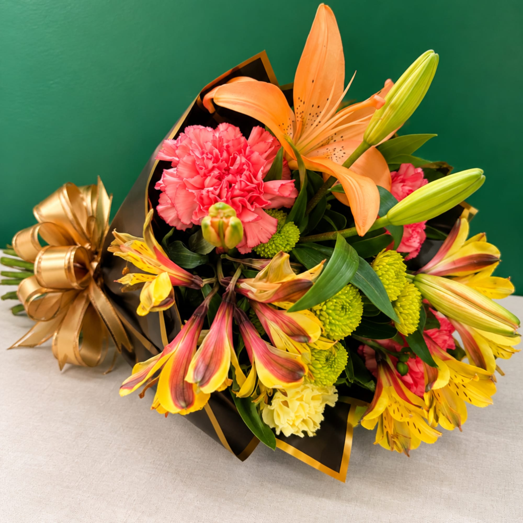 Bouquet of orange lilies, pink carnations, and yellow alstroemeria wrapped in black paper