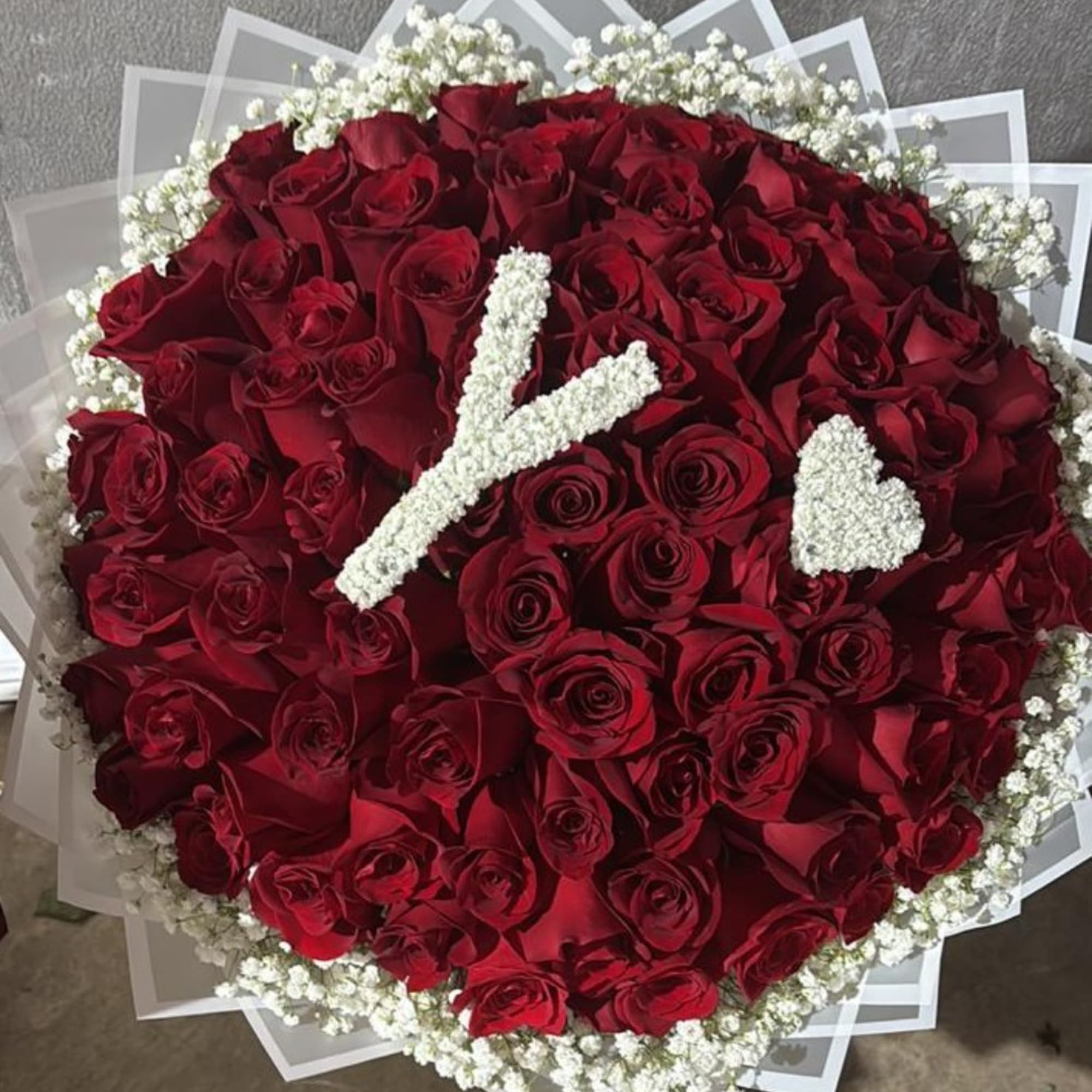 Round bouquet of red roses with white baby's breath accents