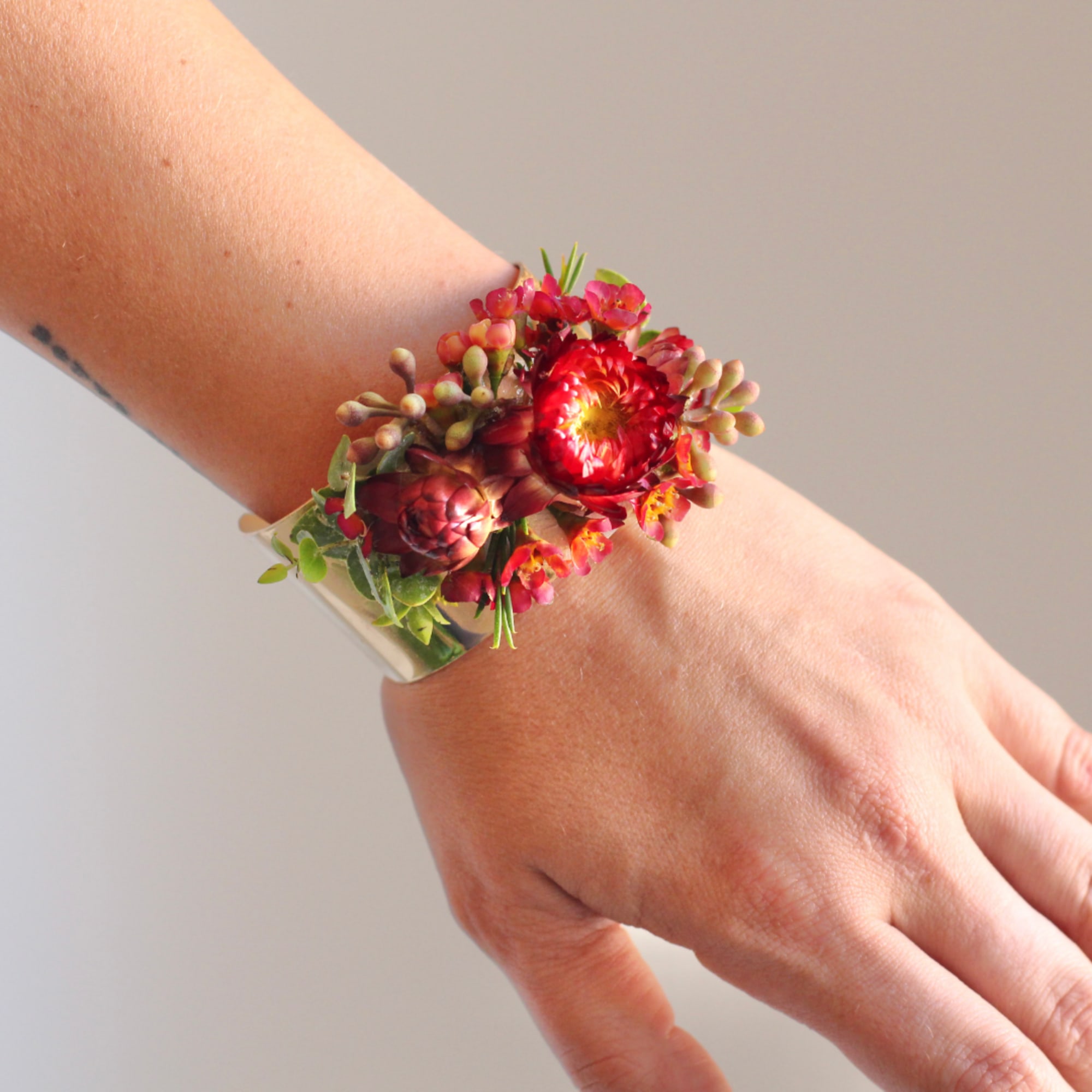 Red floral wrist corsage on a silver cuff bracelet
