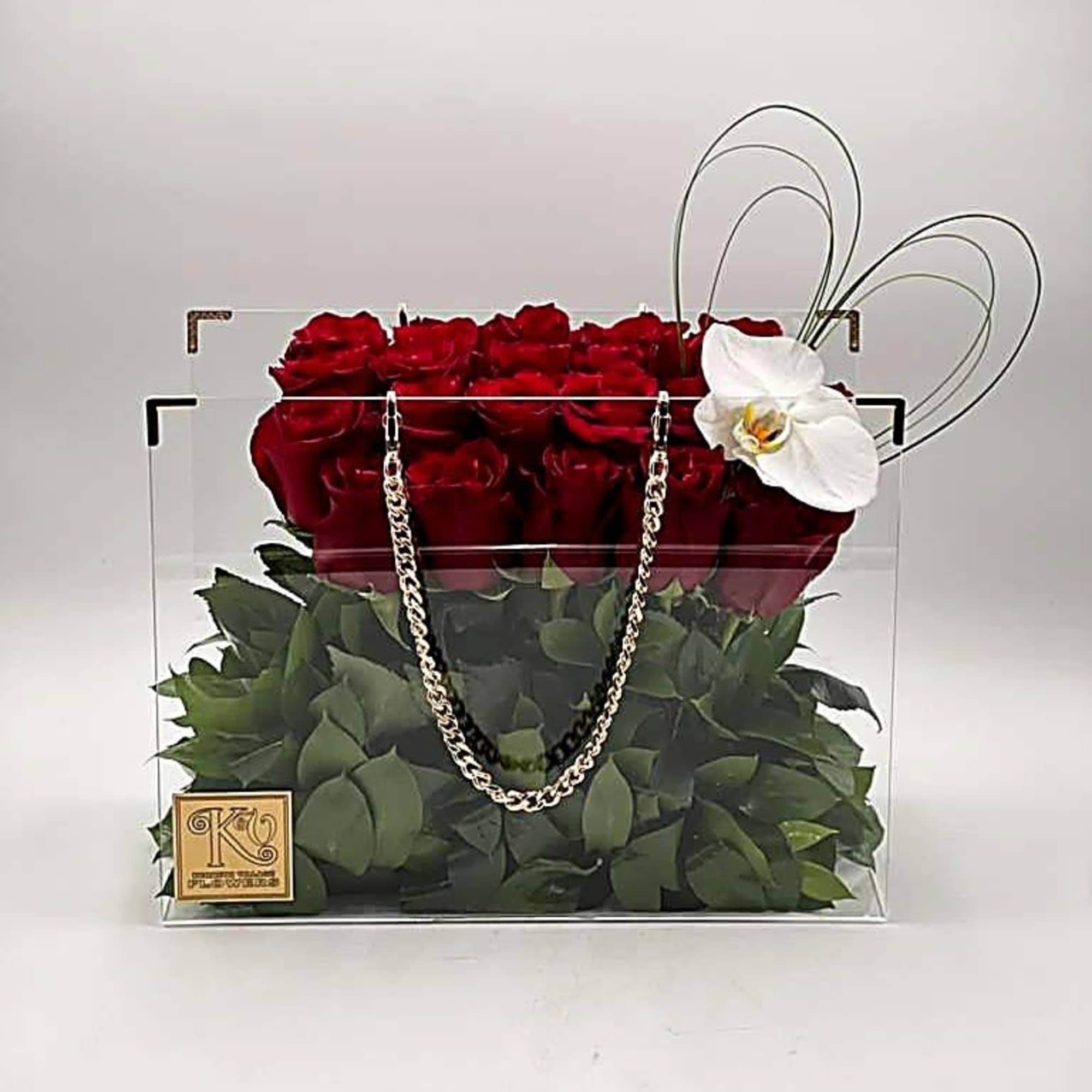 Red roses in a clear square box with a white orchid accent