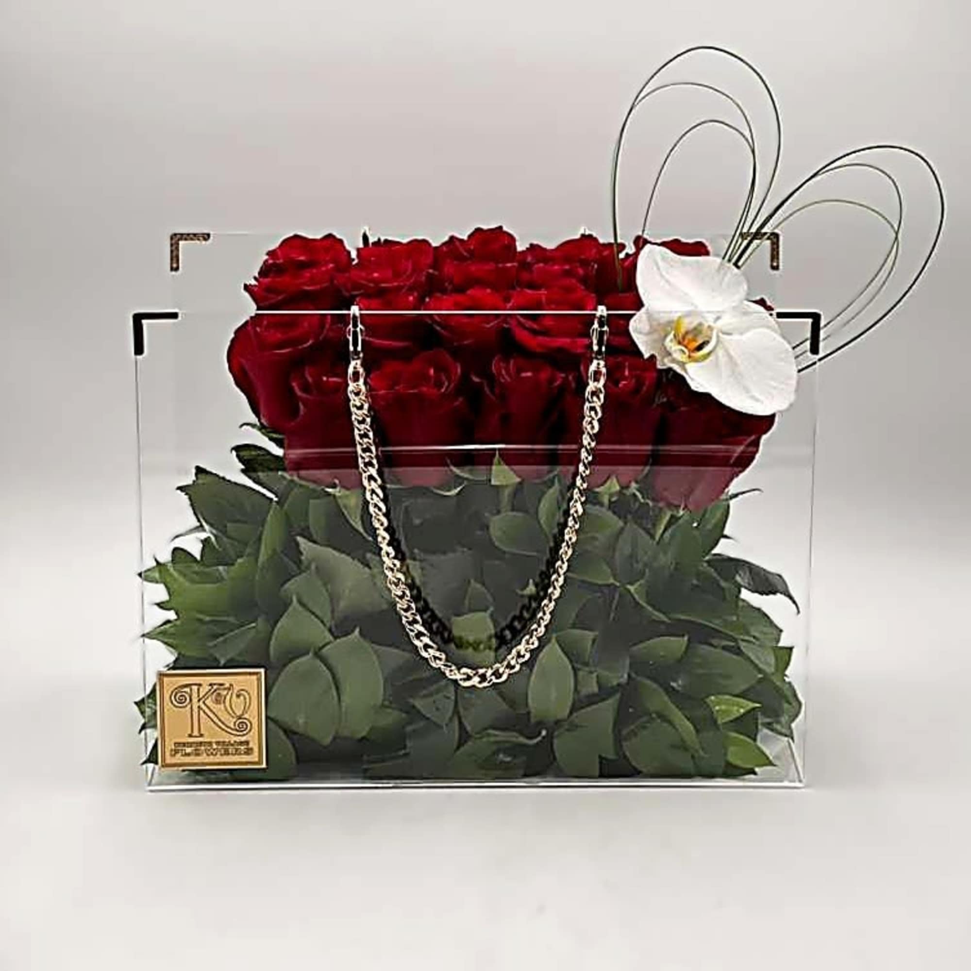 Red roses in a clear handbag-style box with a white orchid accent