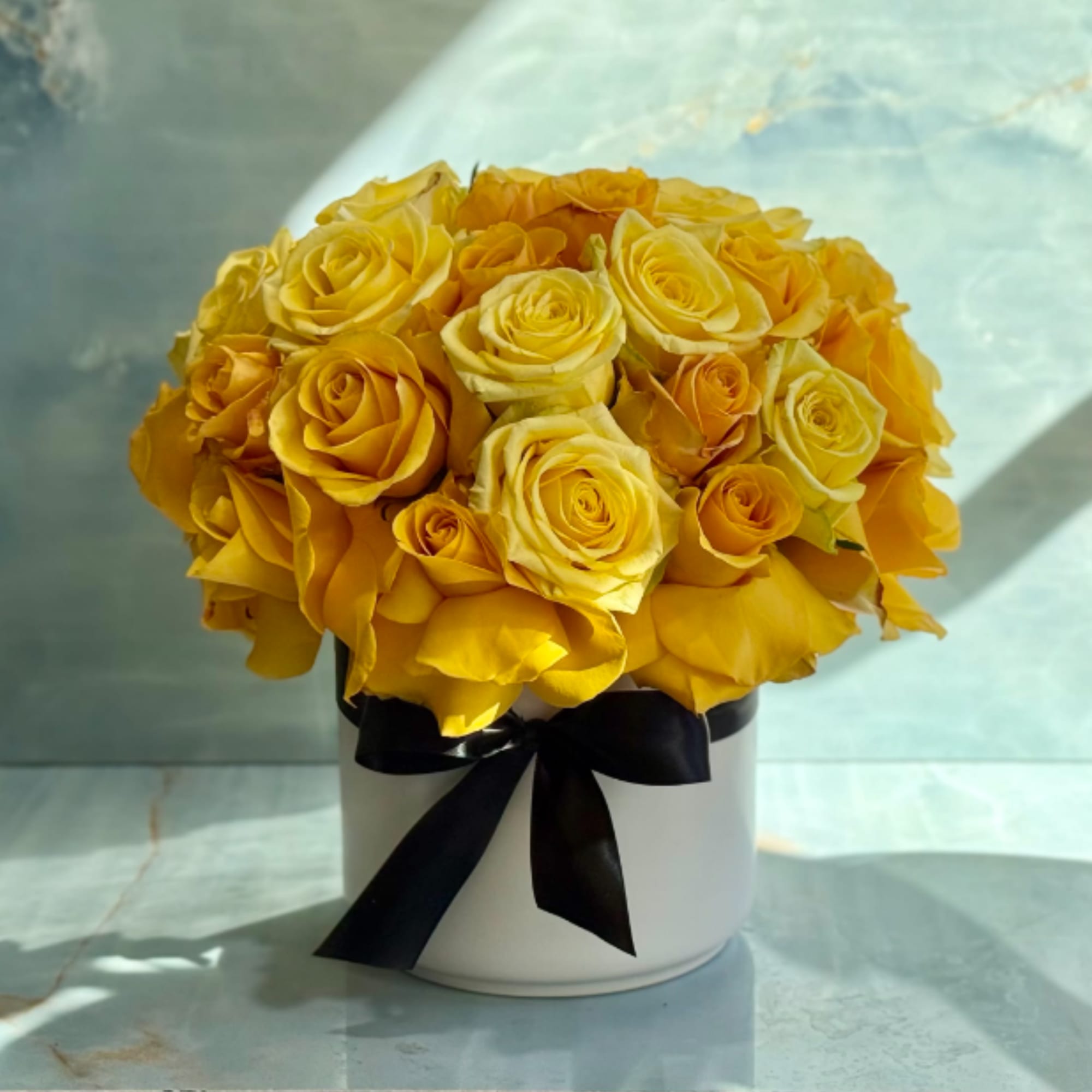 Yellow rose bouquet in a white hatbox with a black ribbon