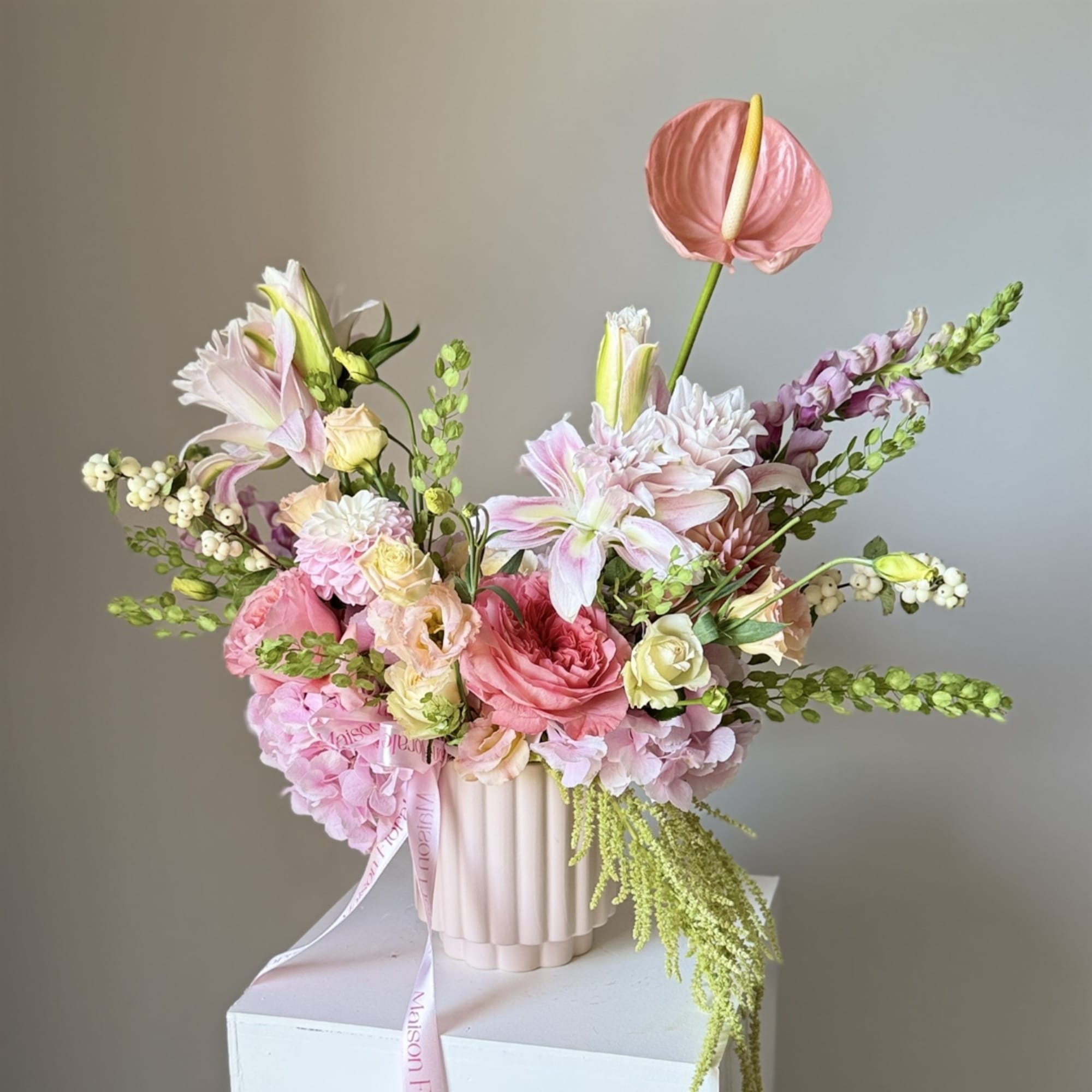 Pink and white floral arrangement in a ribbed vase with a ribbon
