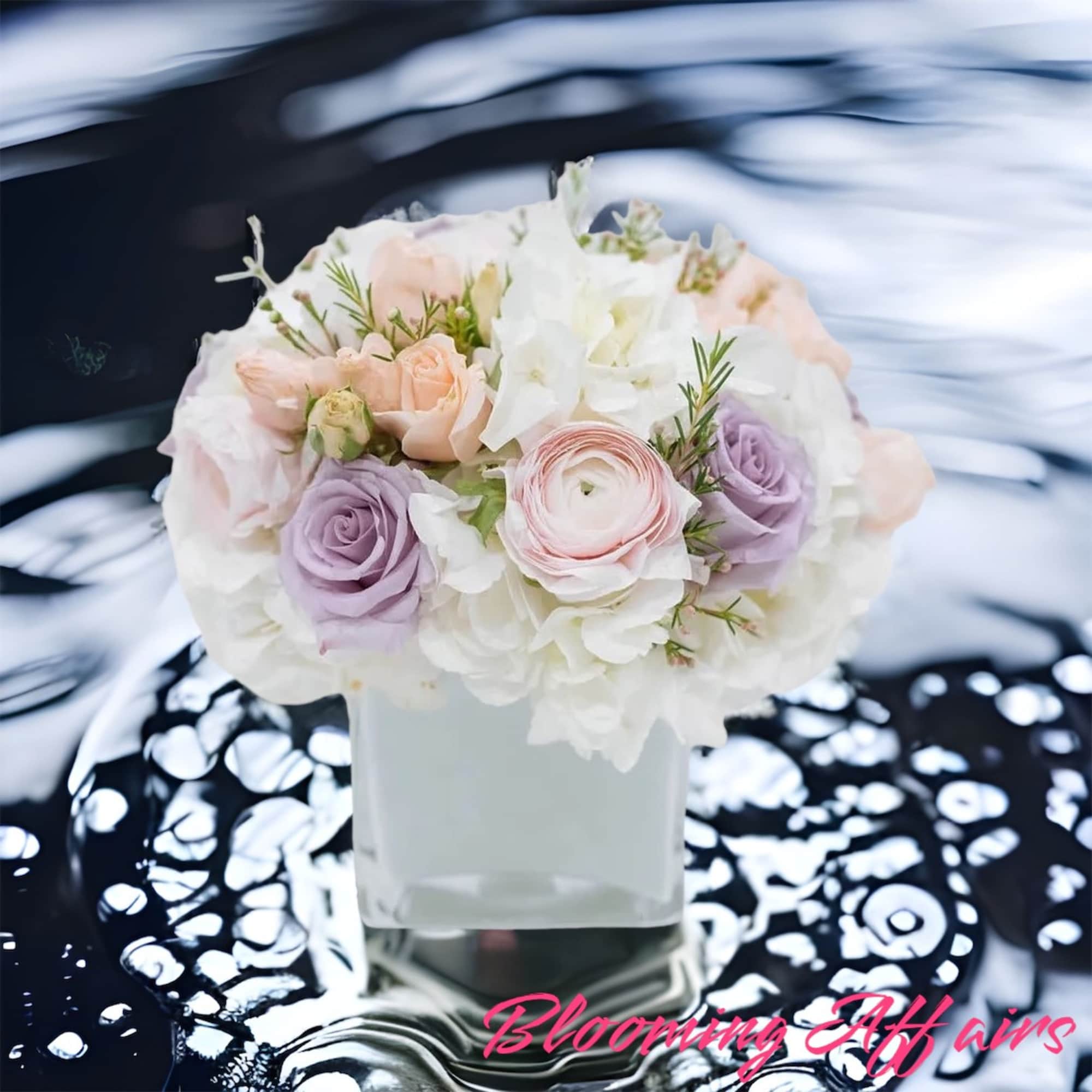 Pastel roses and white blooms arranged in a square glass vase