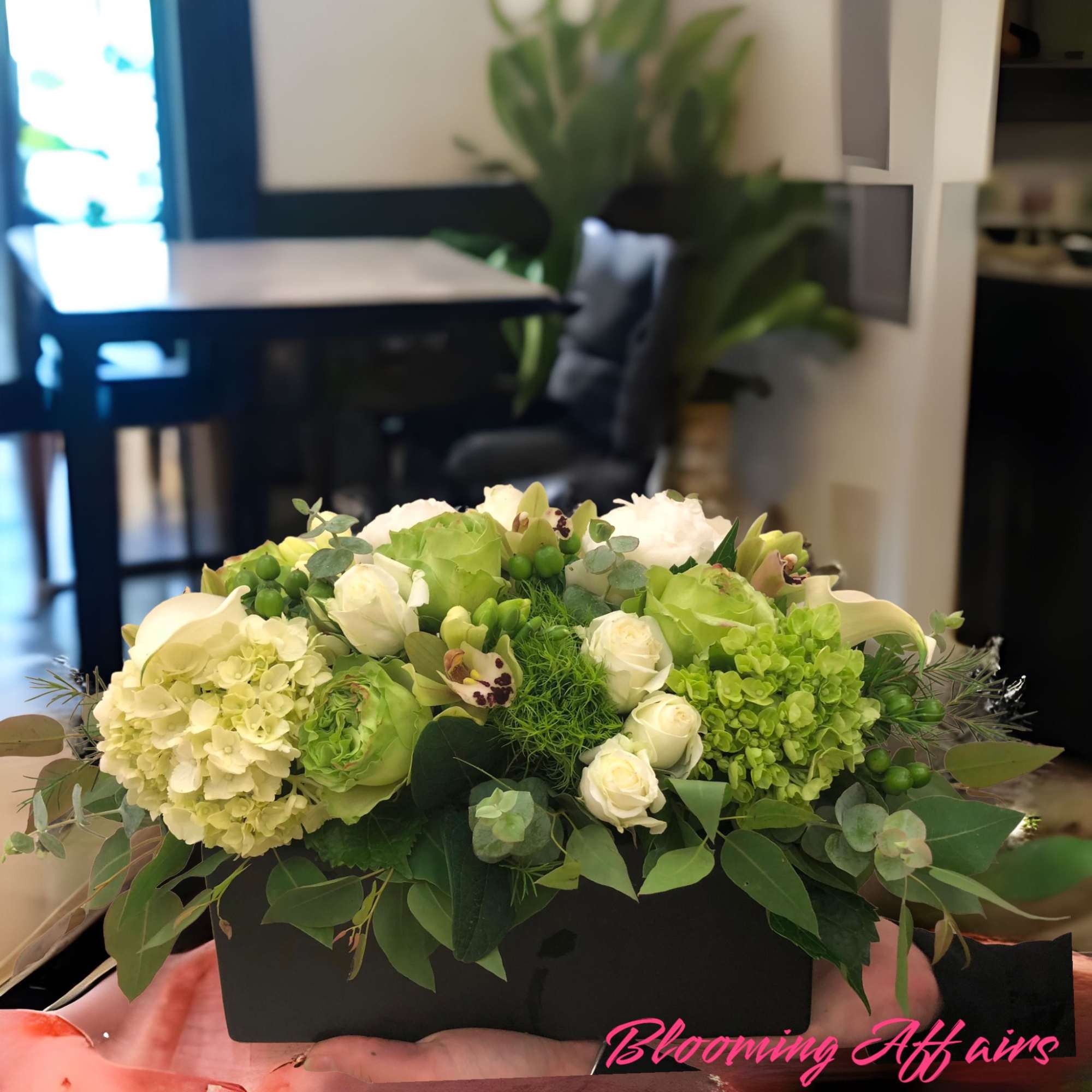 Green and white floral arrangement in a black rectangular box