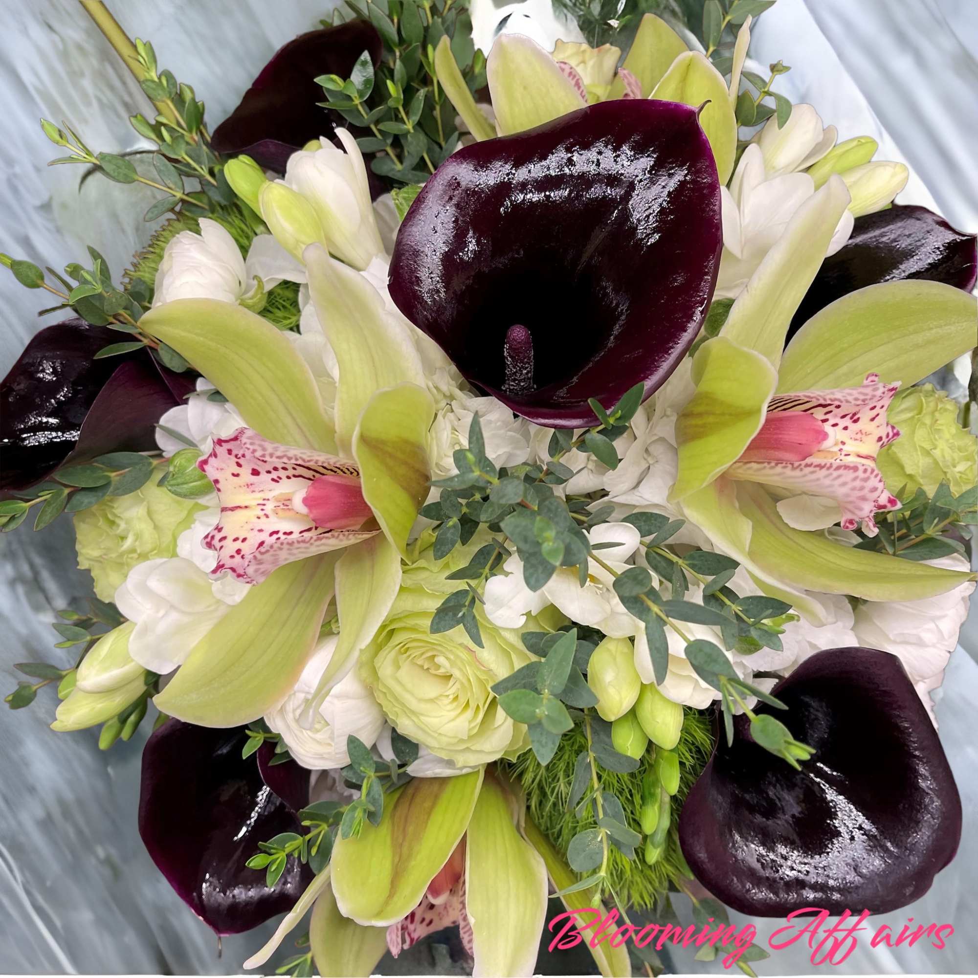 Bouquet of dark purple calla lilies, pale green lilies, and white blooms