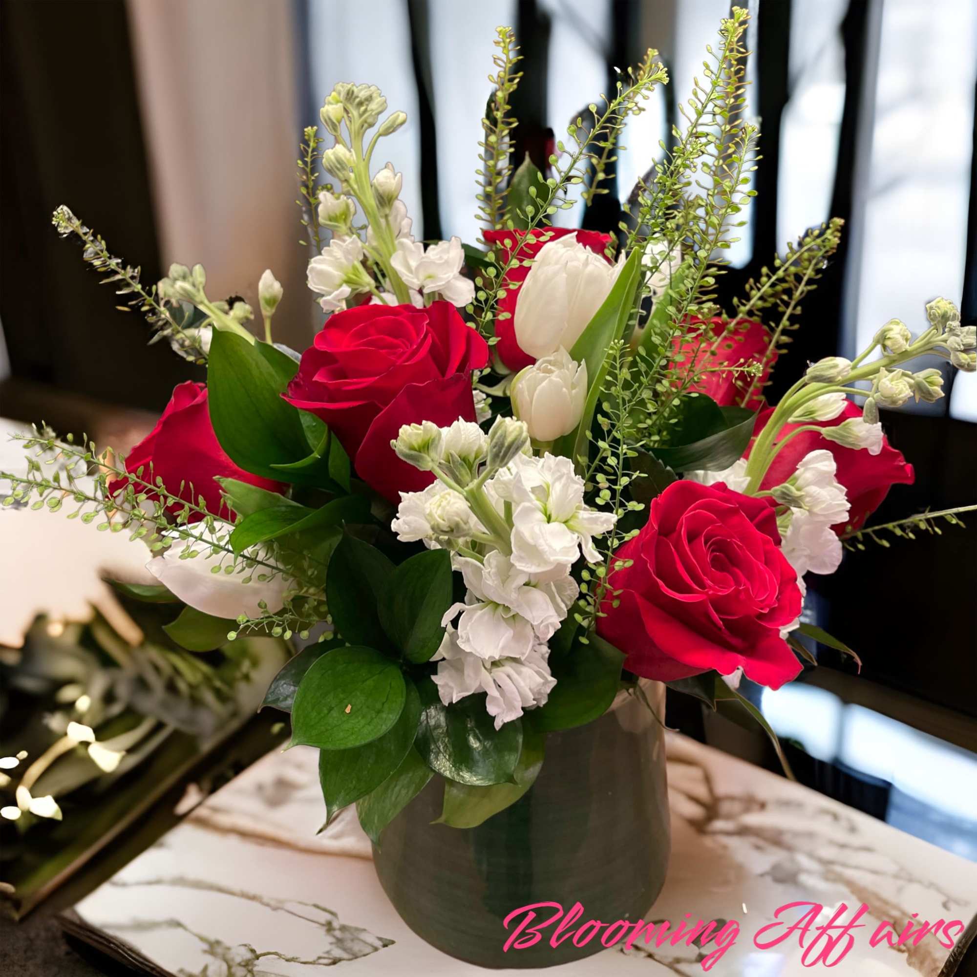 Red roses and white flowers arranged in a gray vase
