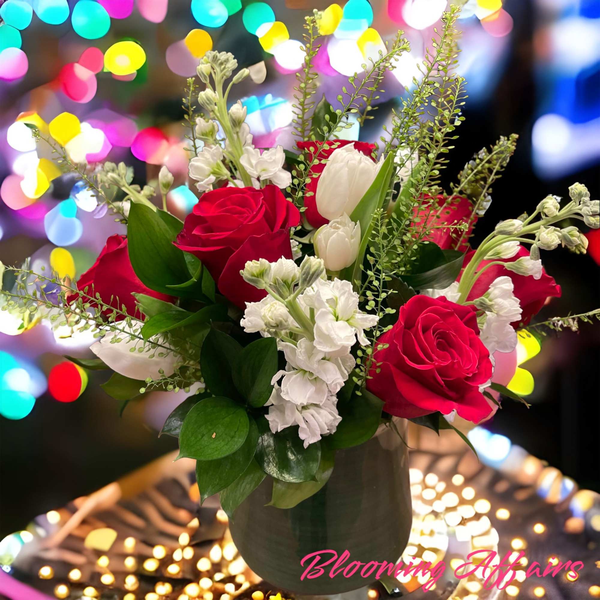 Red and white roses arranged in a dark vase with greenery
