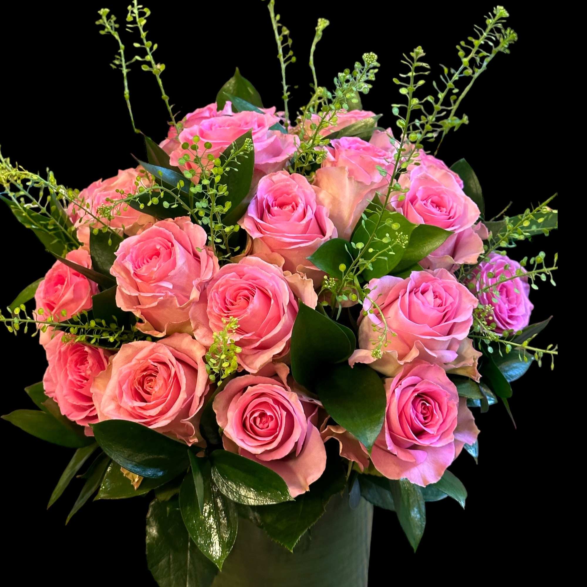 Pink roses arranged in a dark vase with glossy greenery