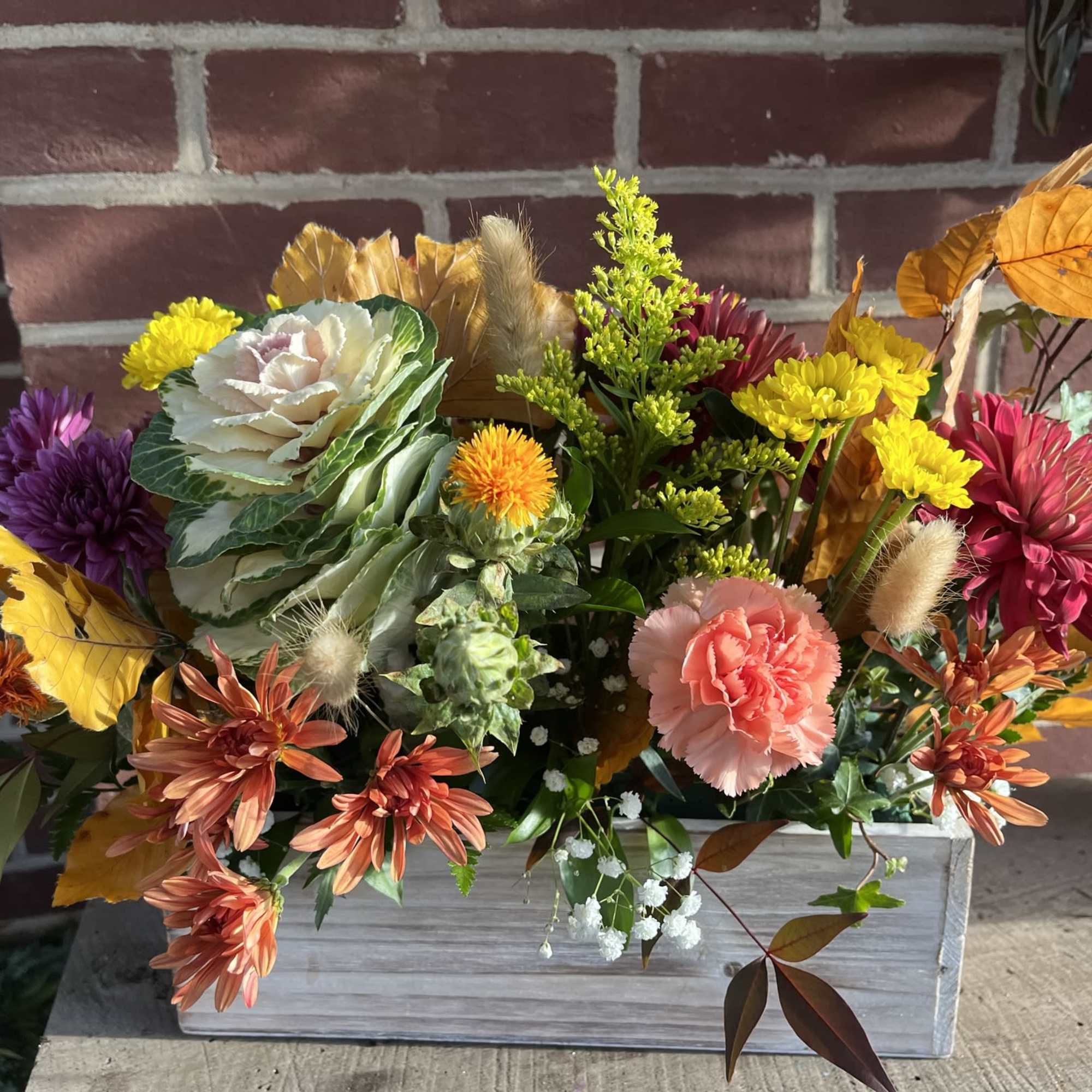 Autumn floral arrangement in a white wooden box with chrysanthemums and carnations