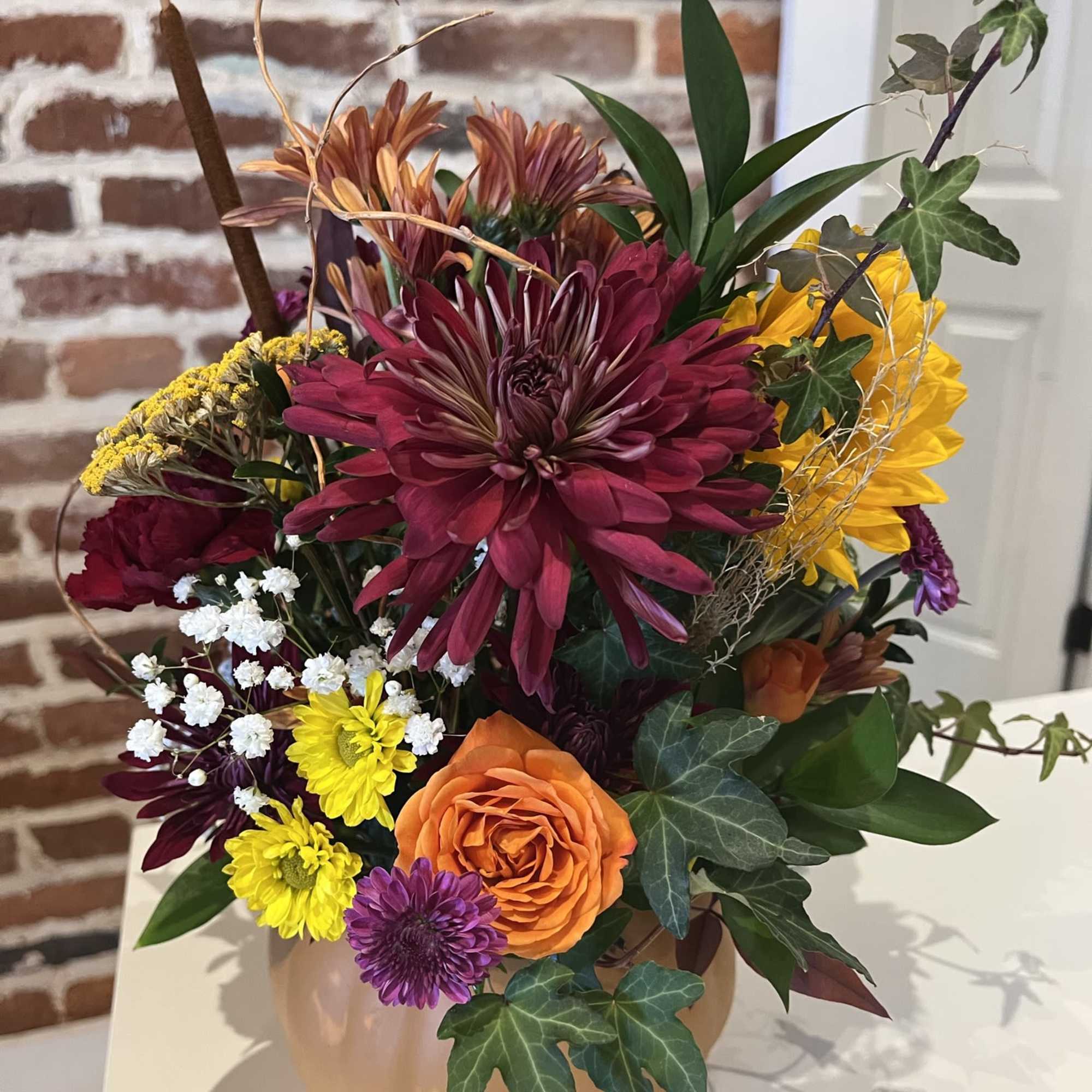 A ceramic pumpkin filled with seasonal flowers, grasses, and greens ready to, photo 2 of 2