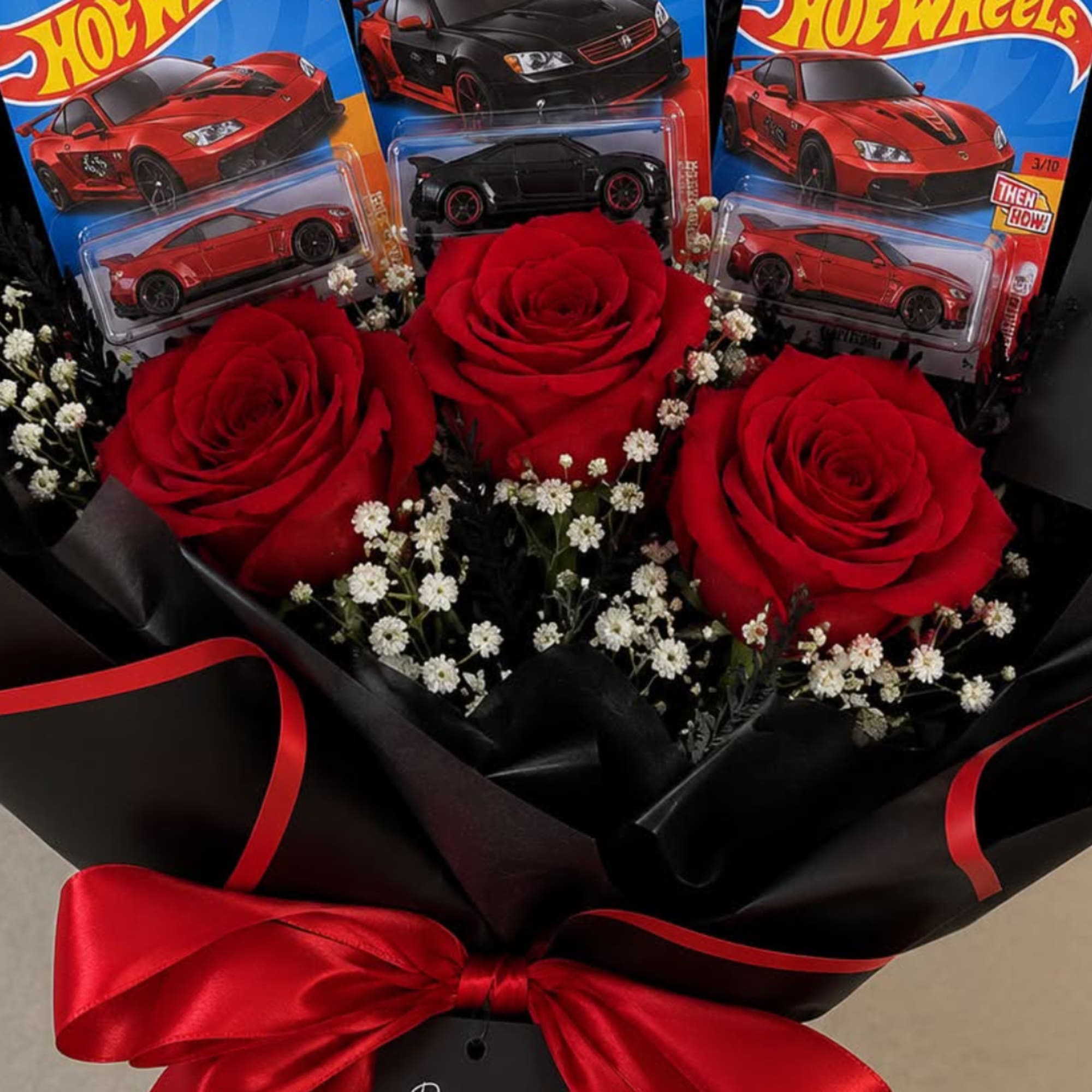Bouquet of red roses with small white filler flowers and toy cars