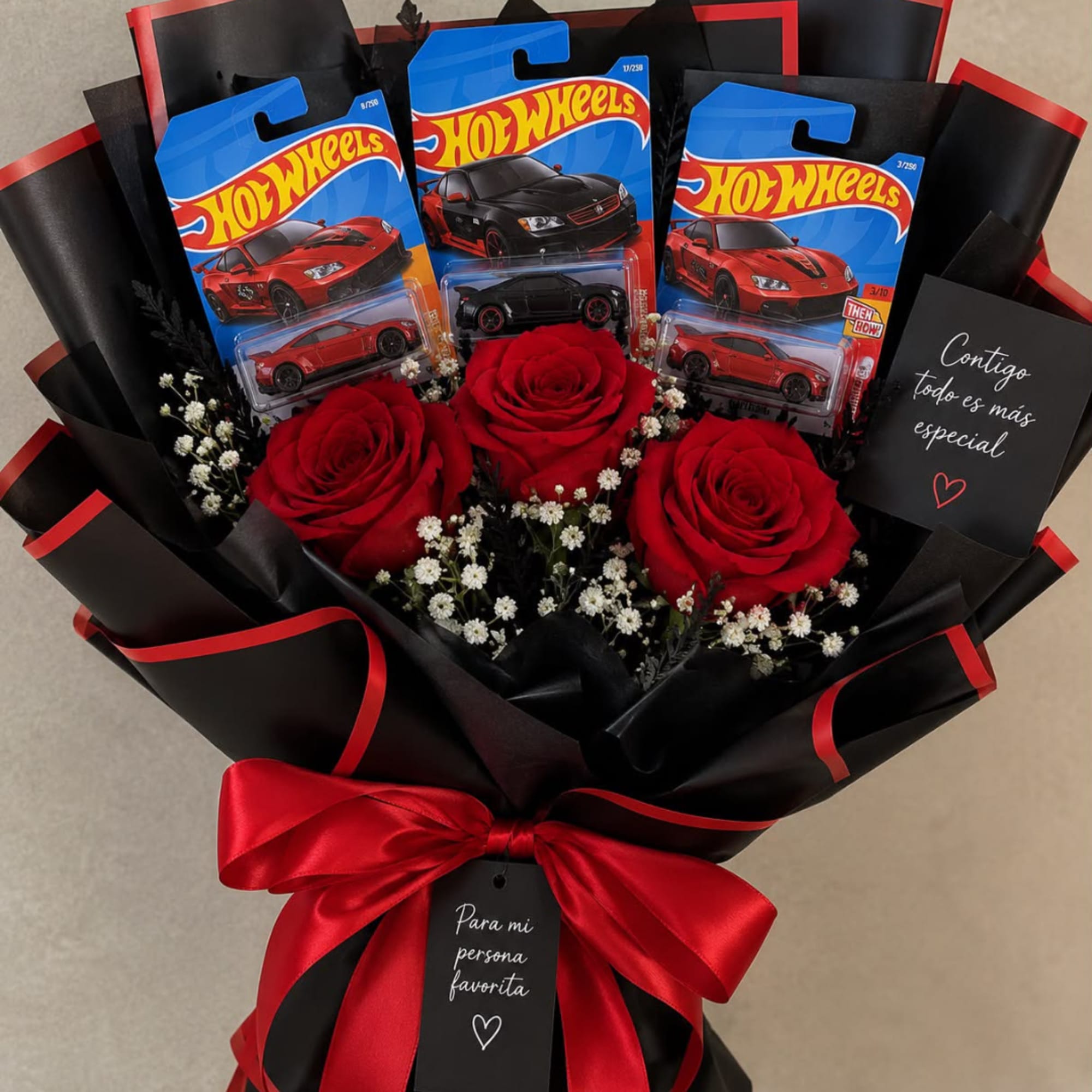 Bouquet of red roses with Hot Wheels toy cars and a red ribbon bow