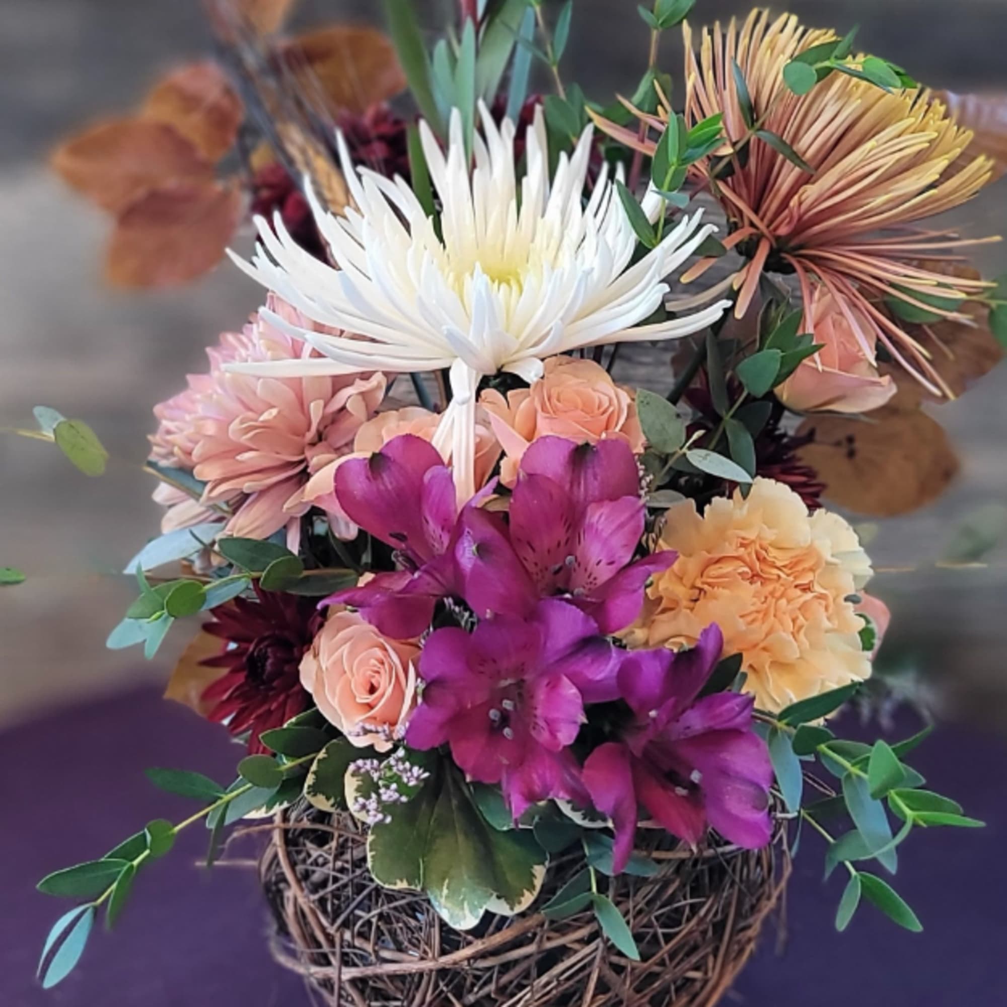 Mixed bouquet with white, purple, peach, and pink flowers in a woven basket