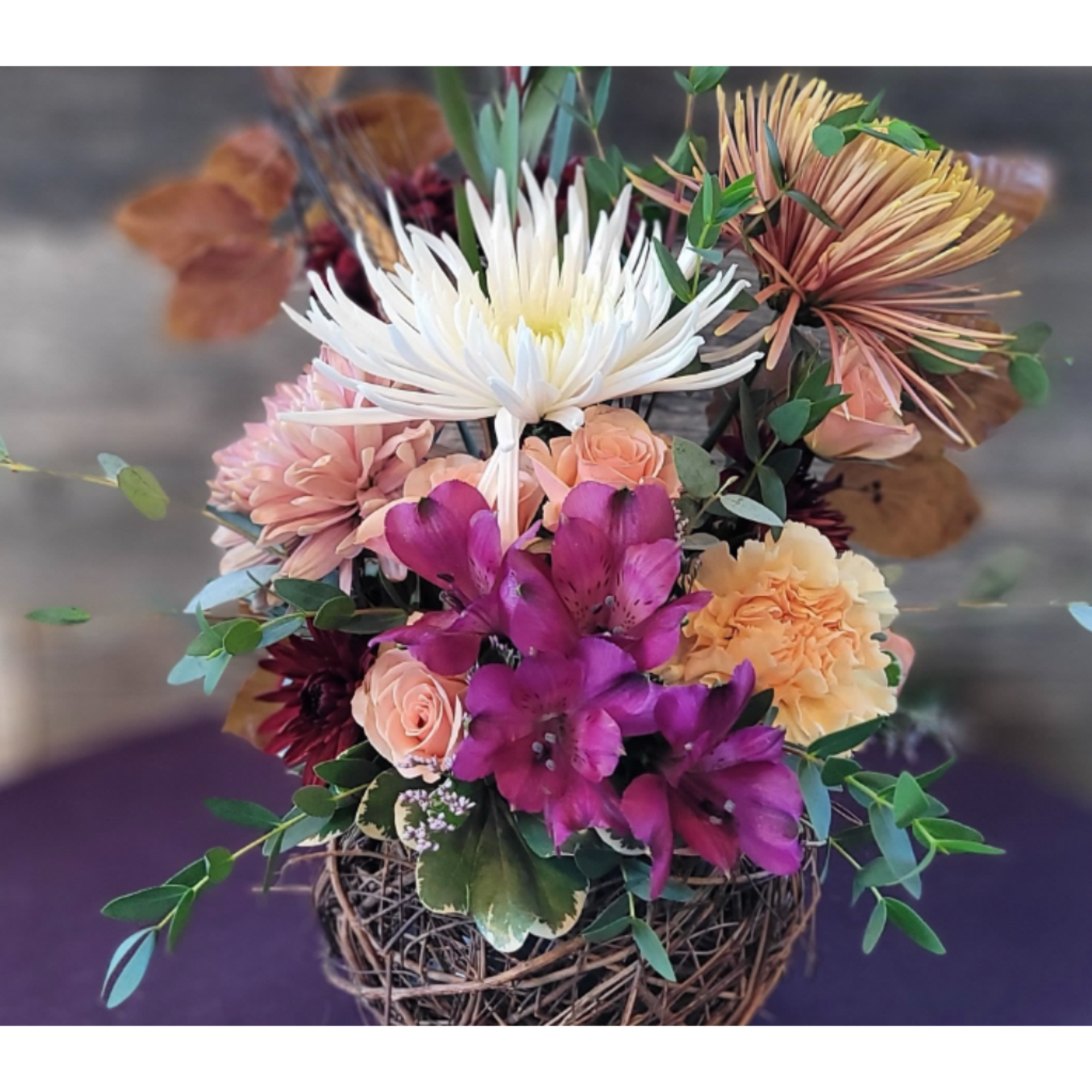 Mixed bouquet in a woven basket with white, purple, and peach flowers