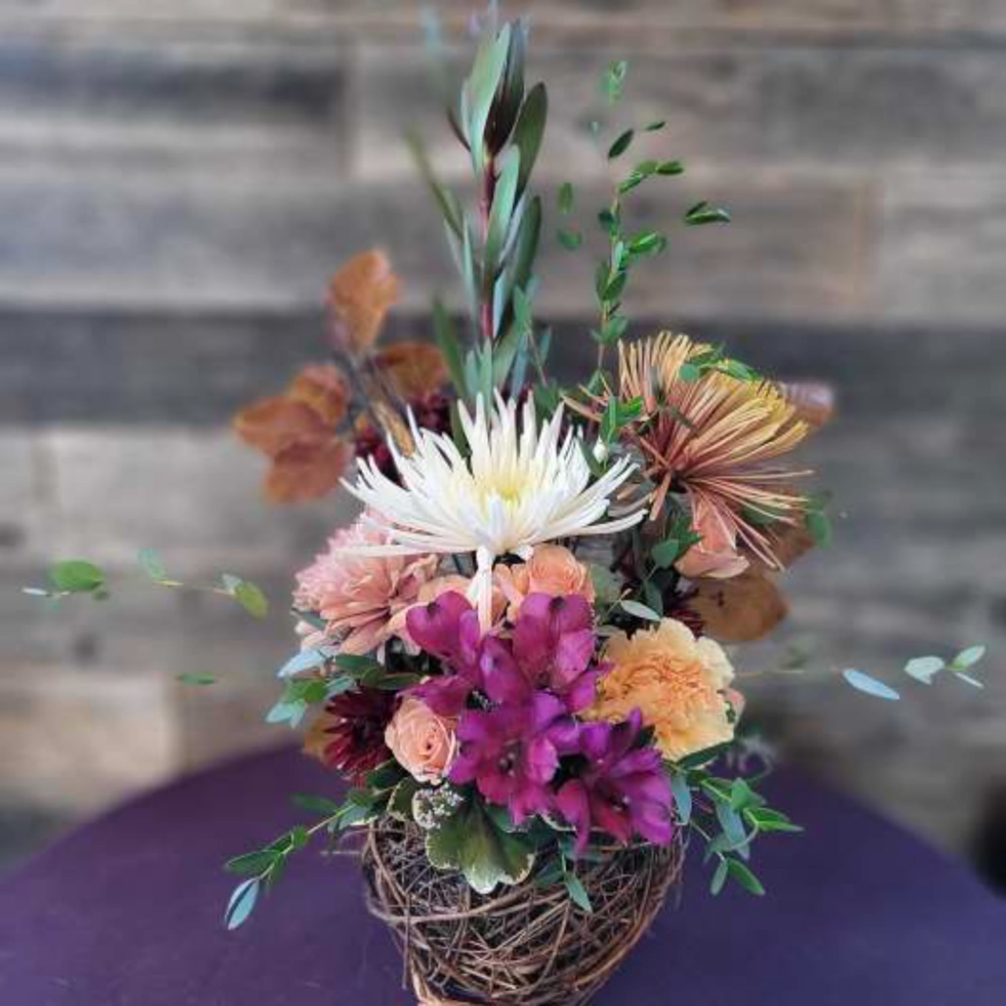 Mixed floral arrangement in a twig basket with white and purple blooms