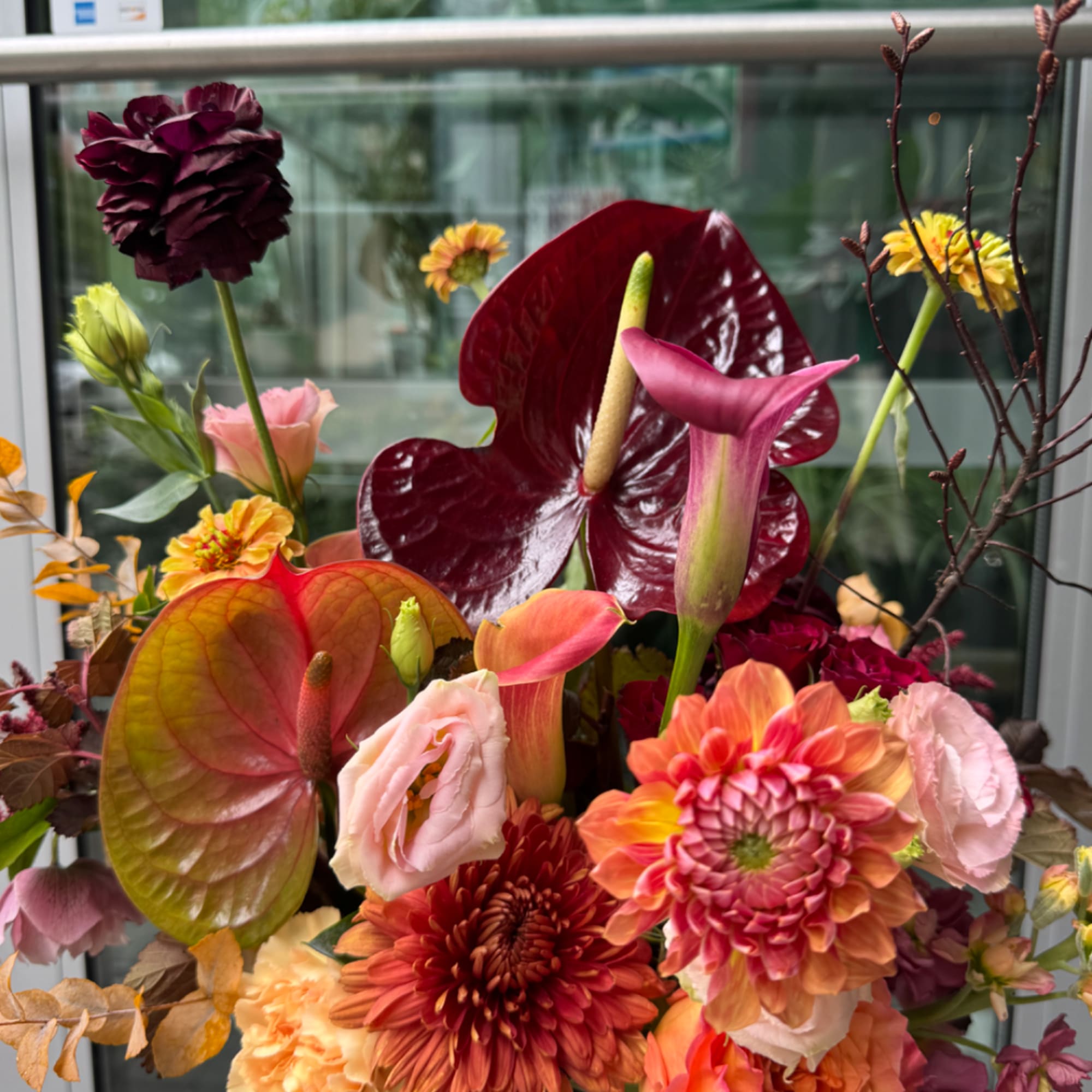 Mixed bouquet with anthuriums, calla lilies, and chrysanthemums in warm pink and burgundy tones