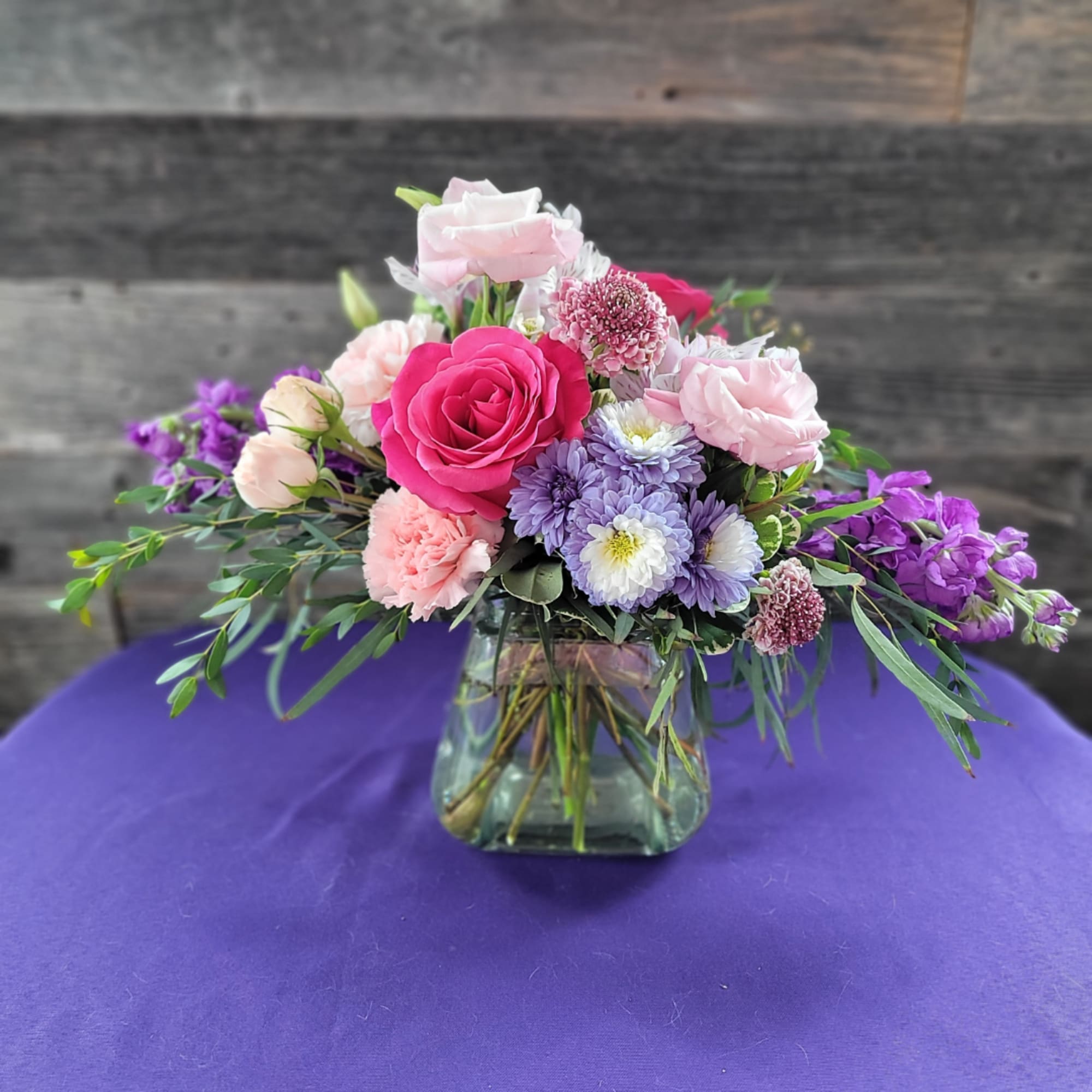 Mixed pink and purple bouquet in a square glass vase