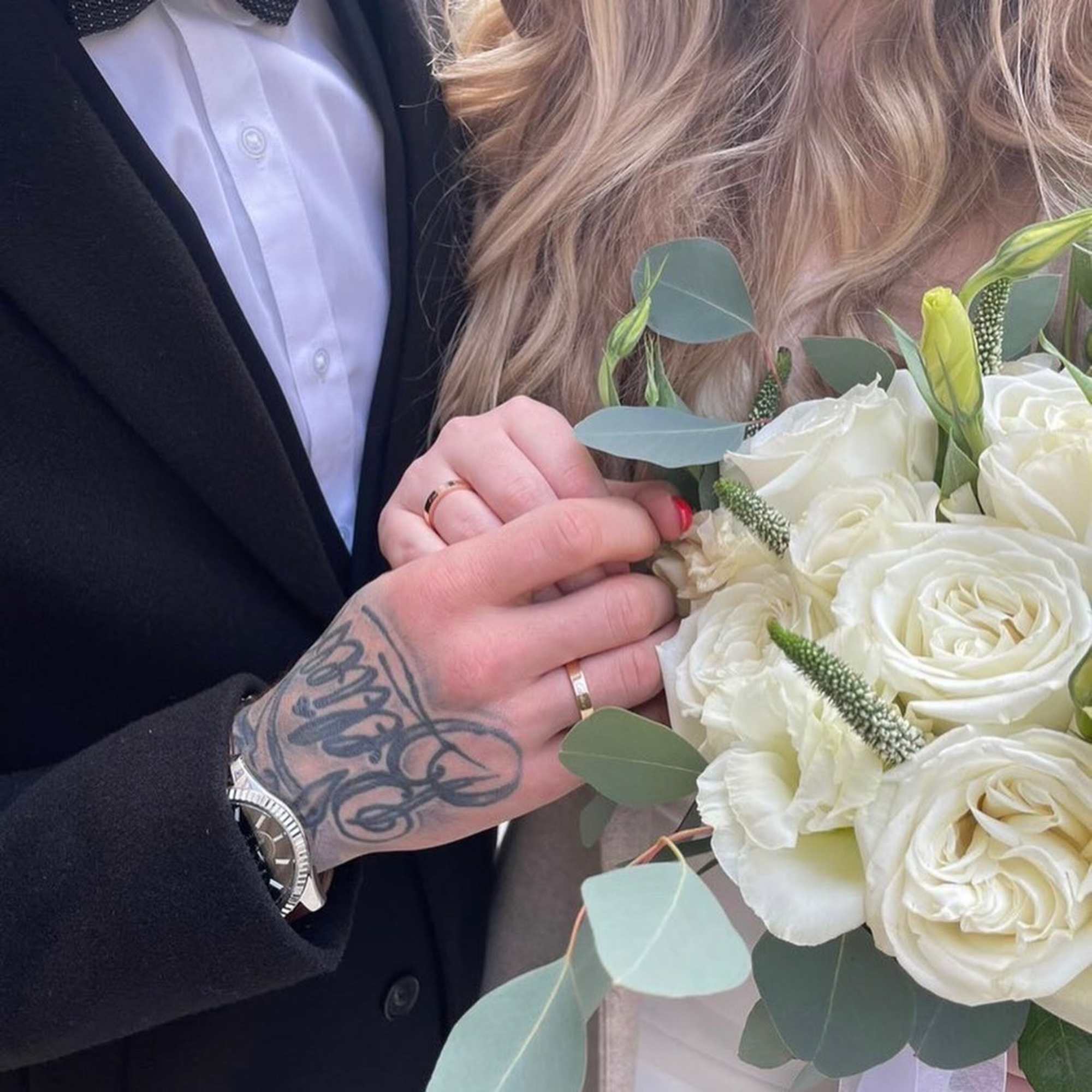 Couple holding a bouquet of white roses with eucalyptus