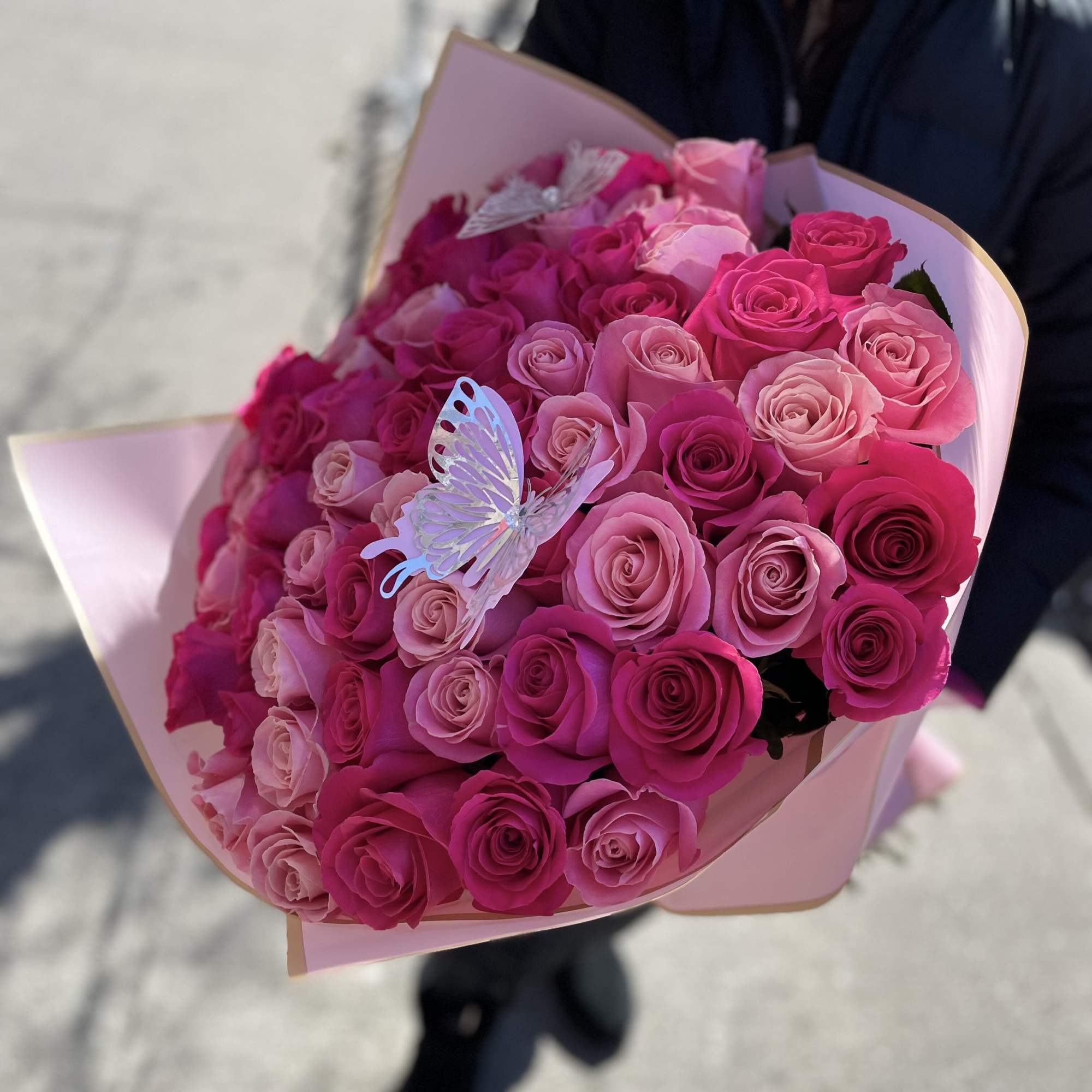 Bouquet of pink roses wrapped in pale pink paper with butterfly accents