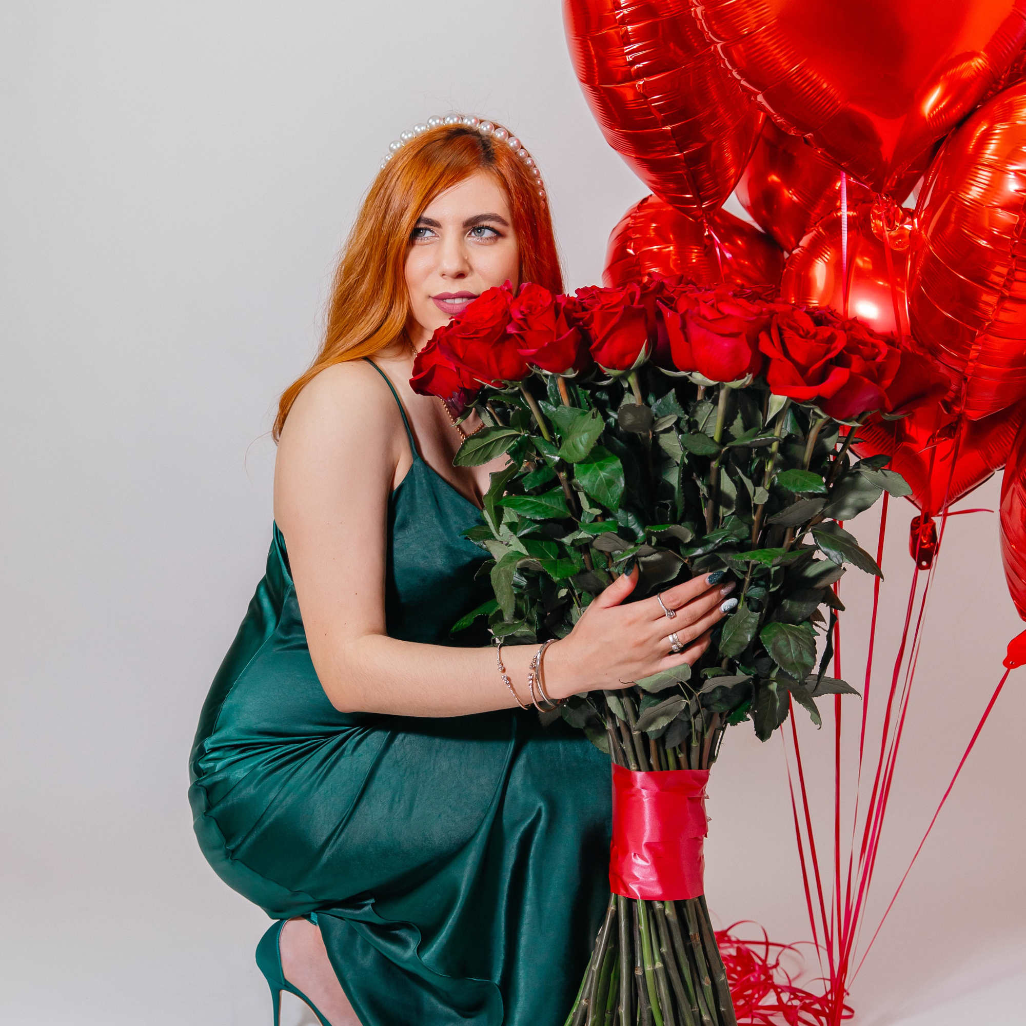 Woman holding a bouquet of red roses with red heart balloons
