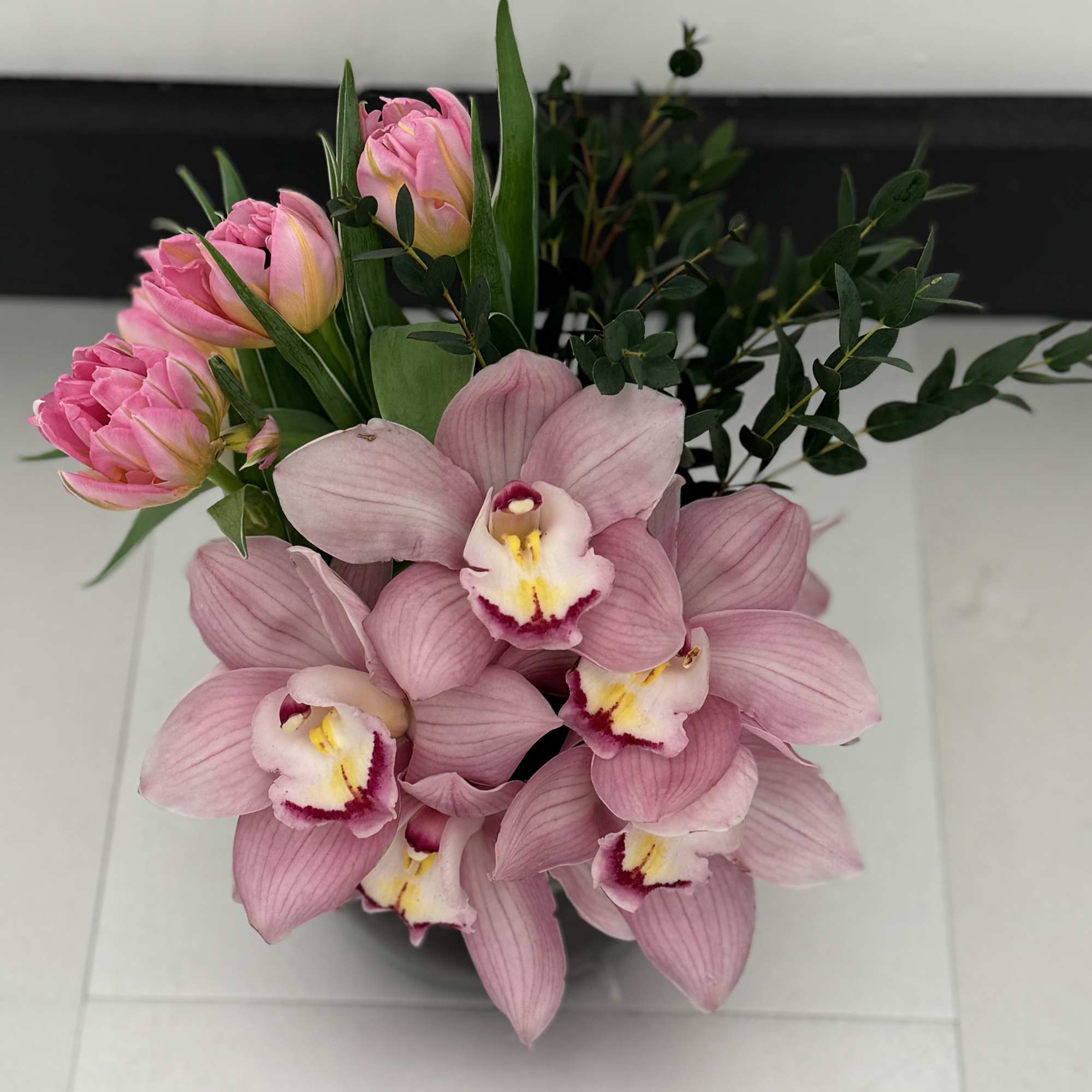 Pink orchids and tulips arranged in a compact bouquet