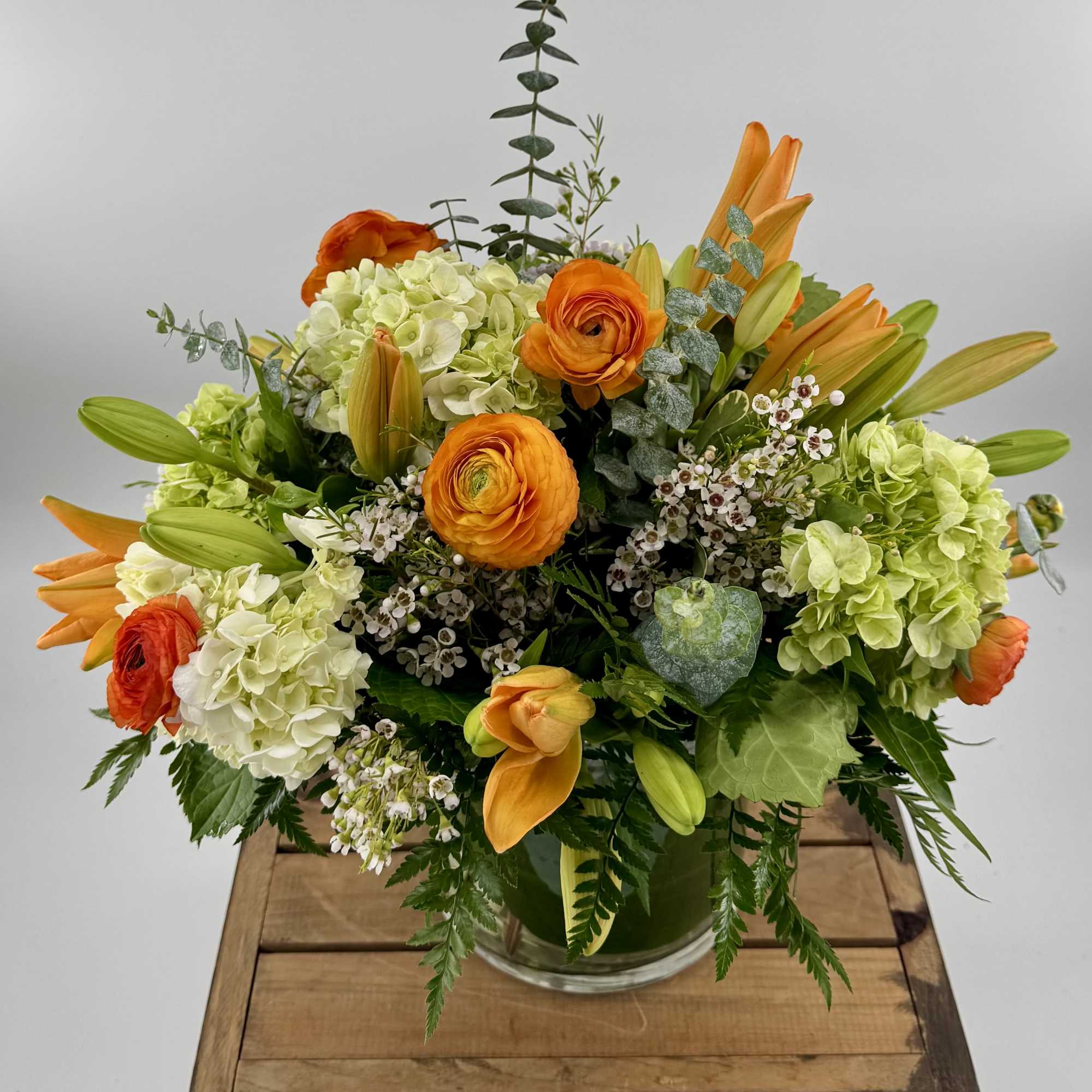 Orange and green floral arrangement in a clear glass vase