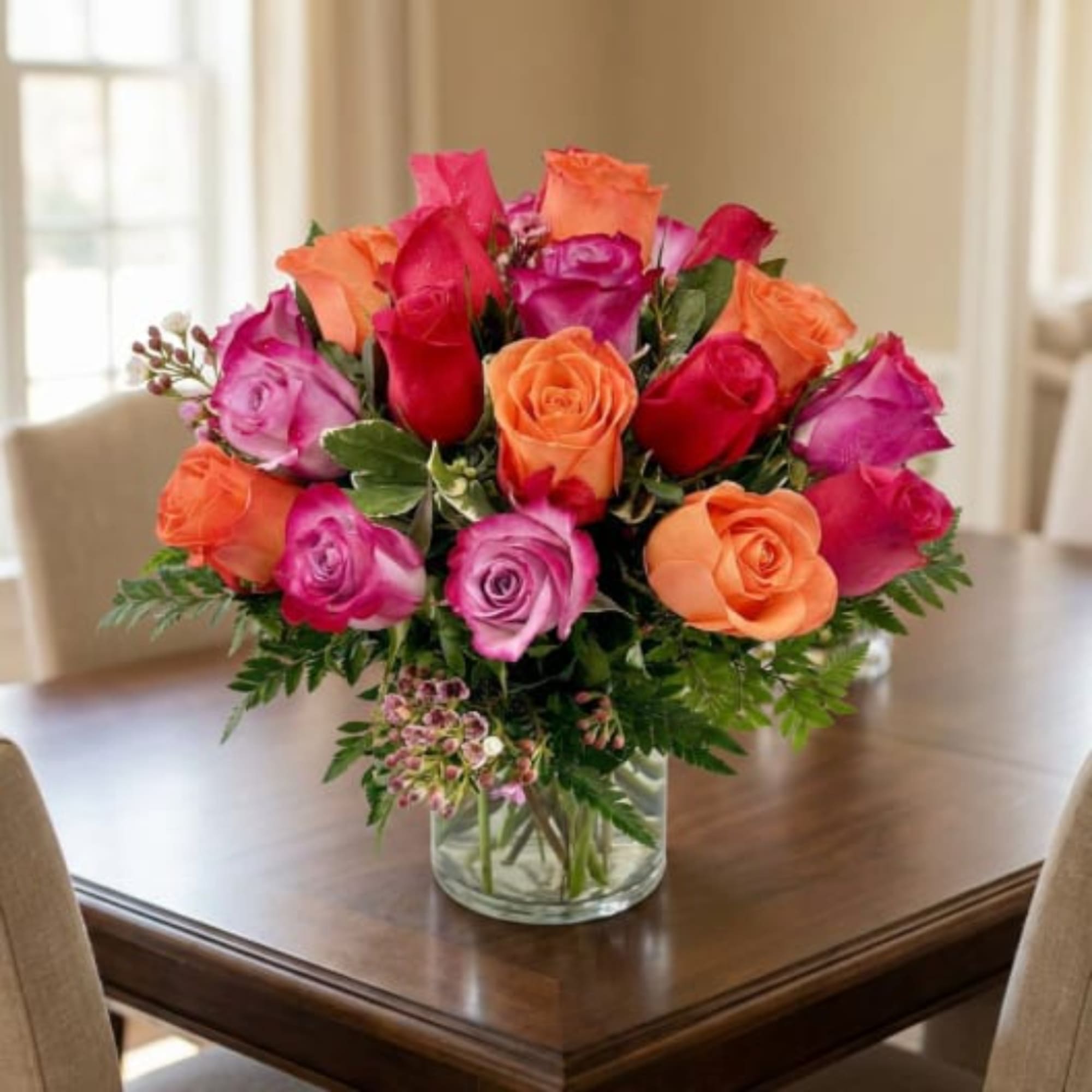 Bouquet of pink, red, and orange roses in a clear glass vase