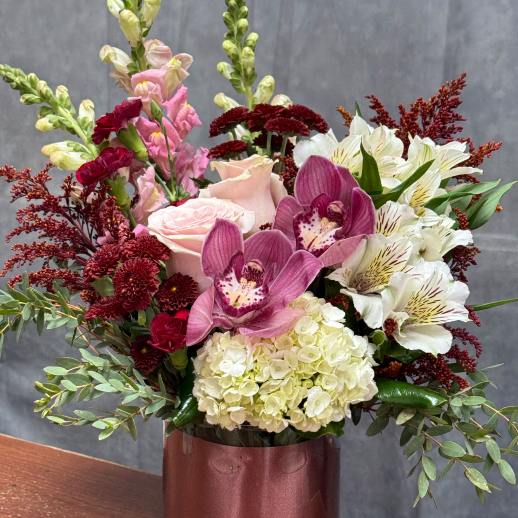 Mixed bouquet with pink roses, orchids, hydrangea, and white alstroemeria in a vase
