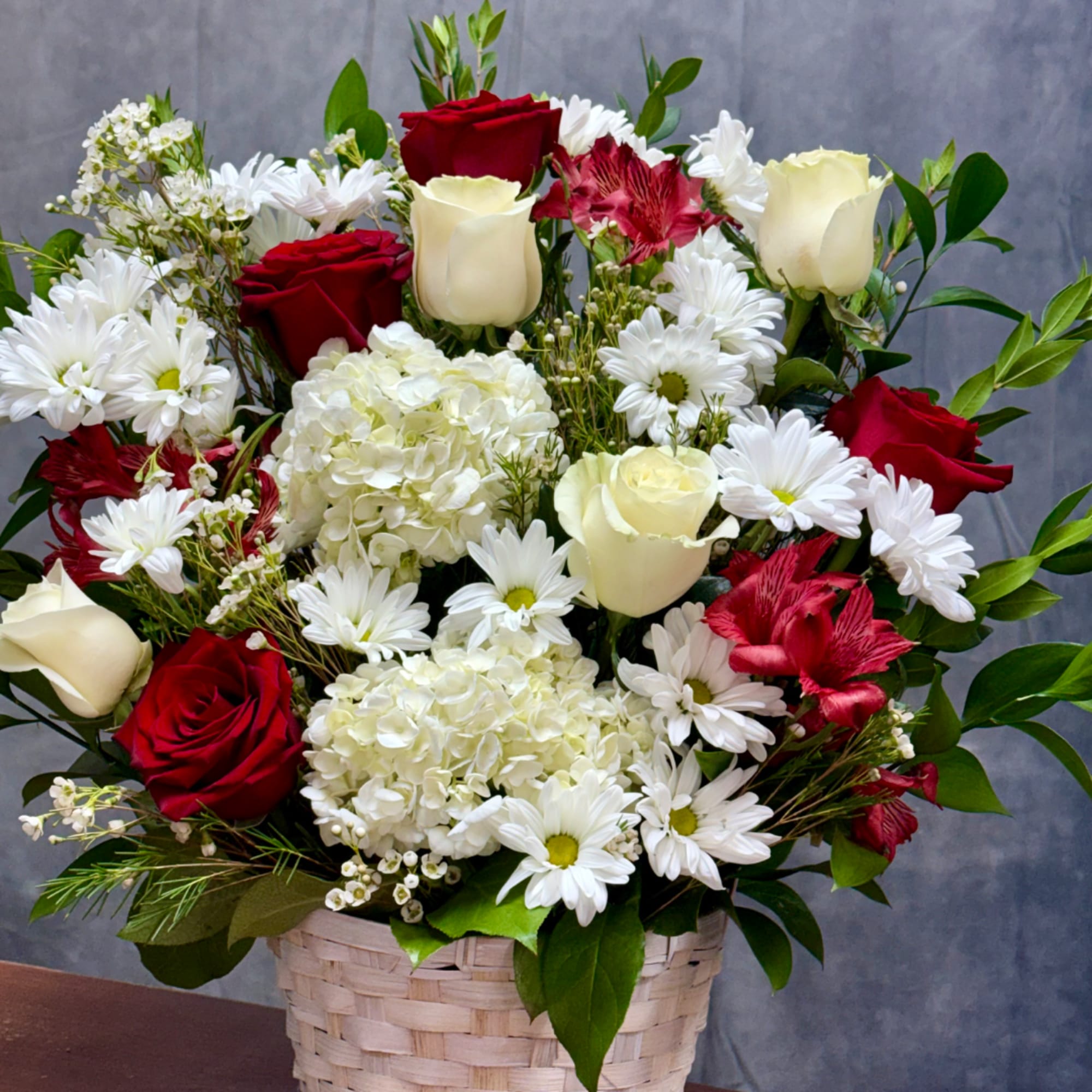 Basket arrangement of red and white roses with white daisies and hydrangeas