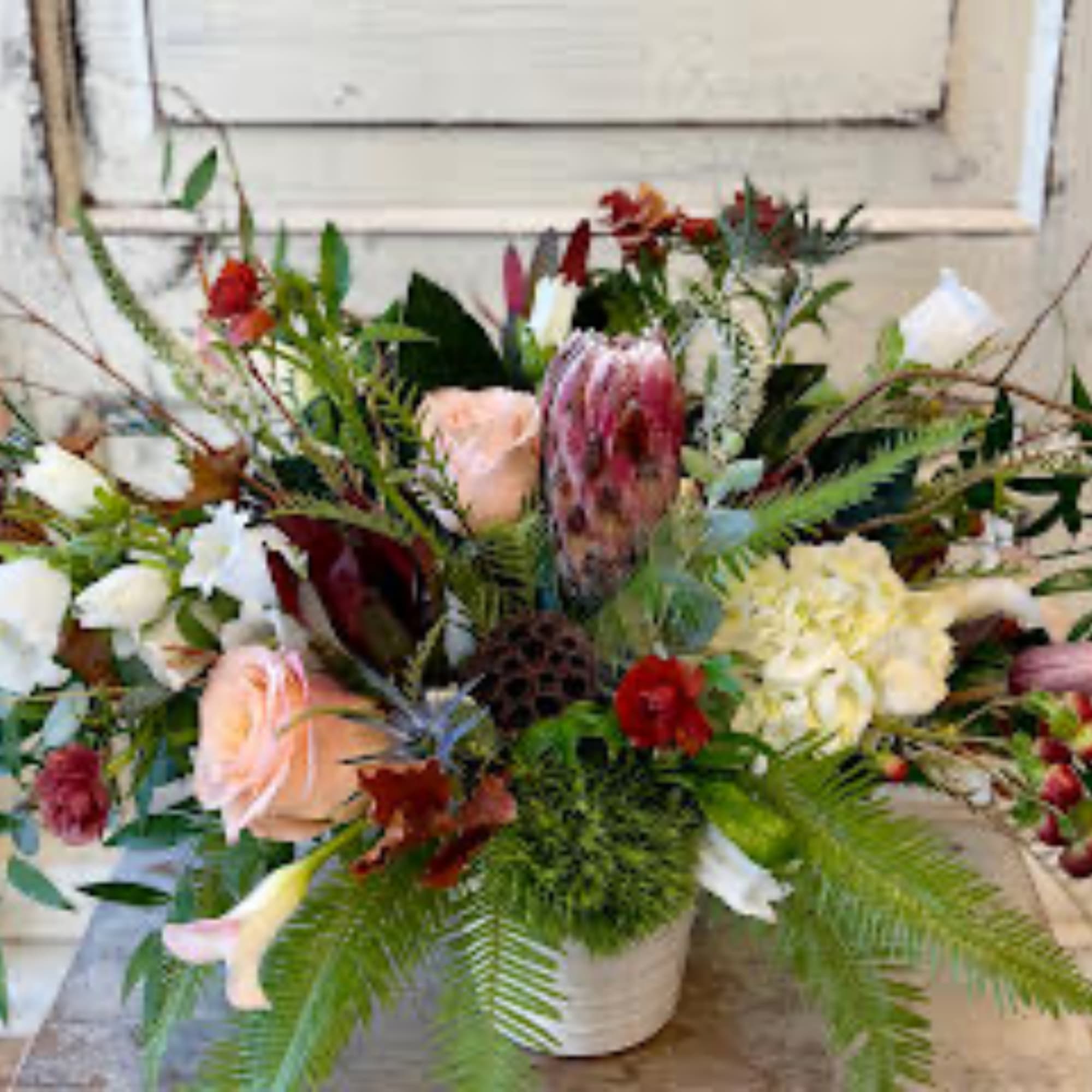 Mixed floral arrangement in a white vase with roses and lilies