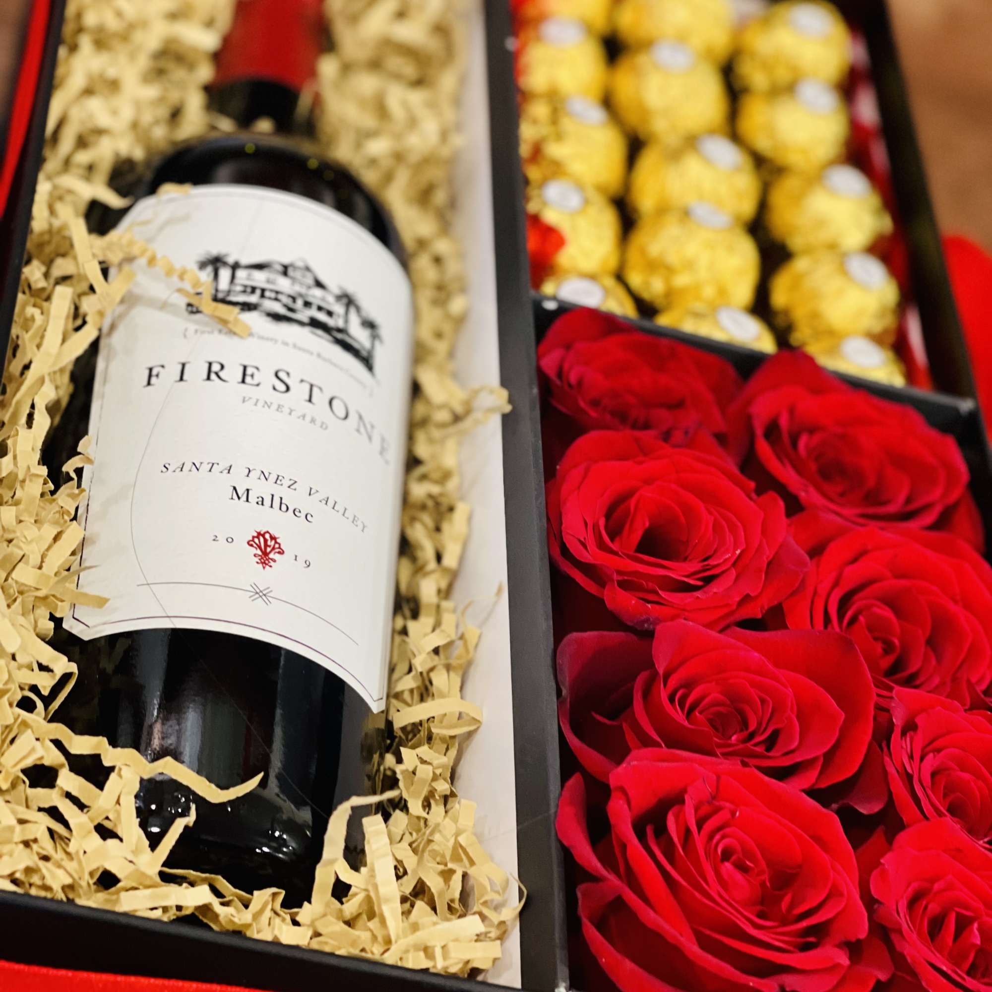 Gift box with a wine bottle, red roses, and gold chocolates