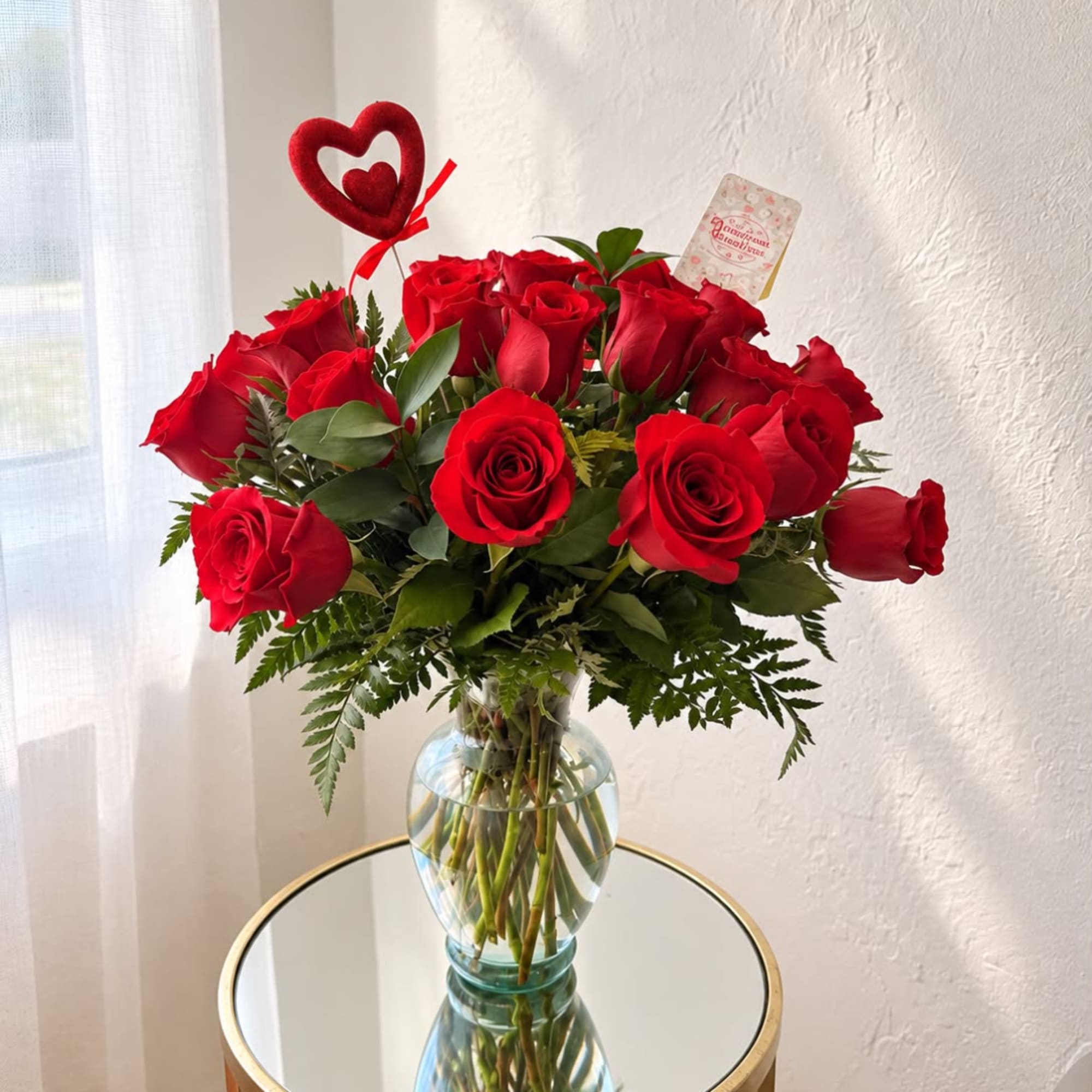 Red roses arranged in a clear glass vase with a heart pick, photo 5 of 5