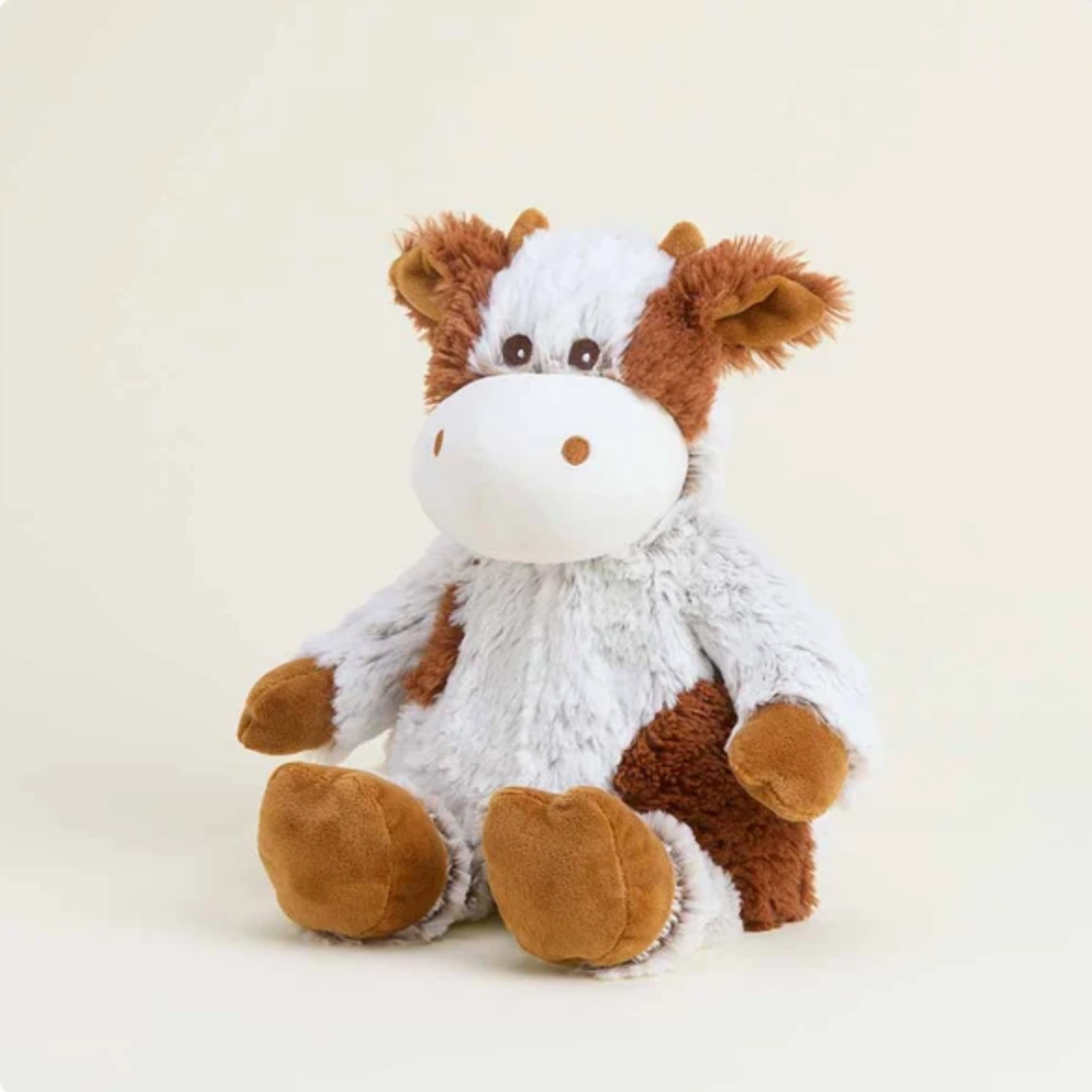 Plush cow stuffed animal sitting against a plain light background