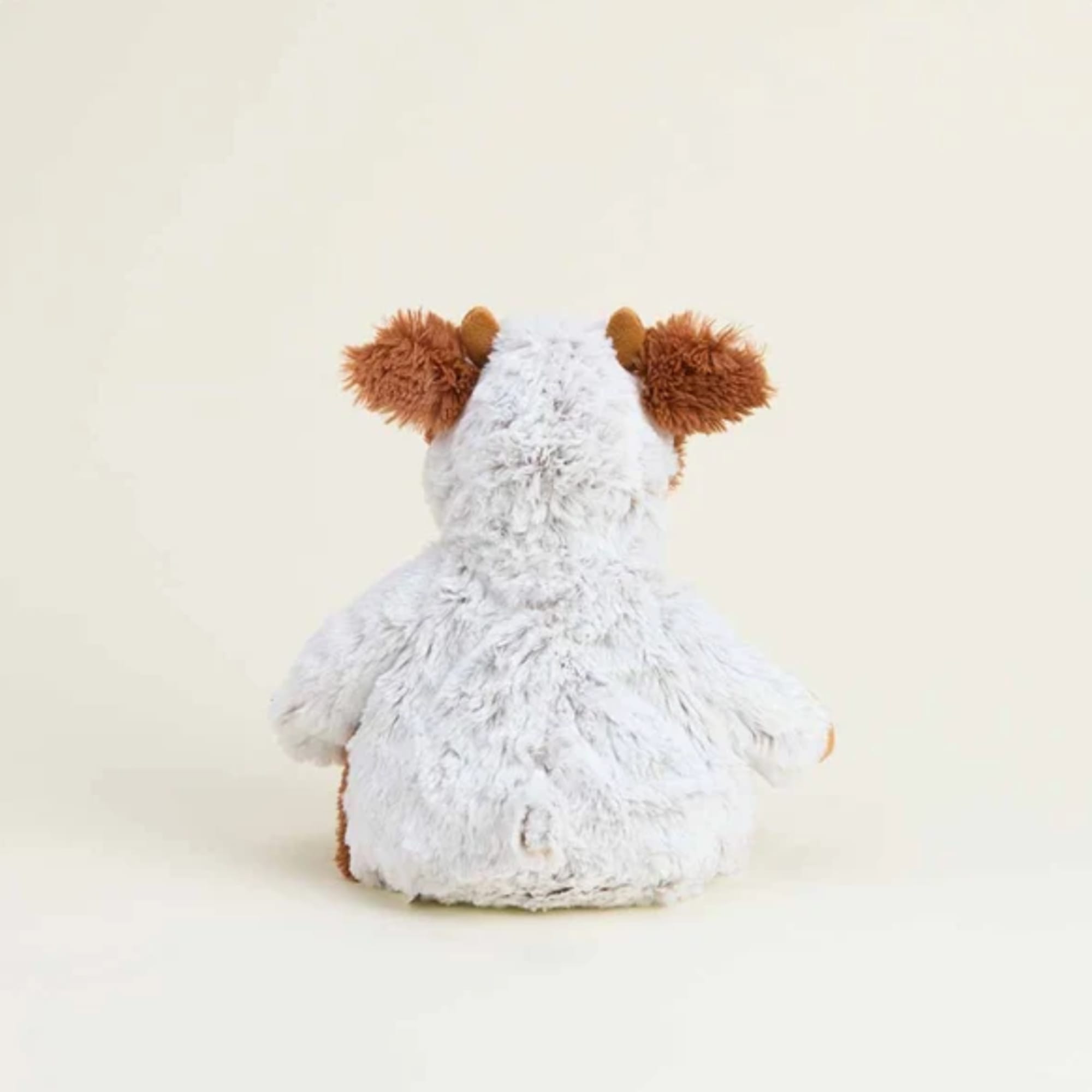 Plush stuffed animal with white fur and brown ears shown from the back