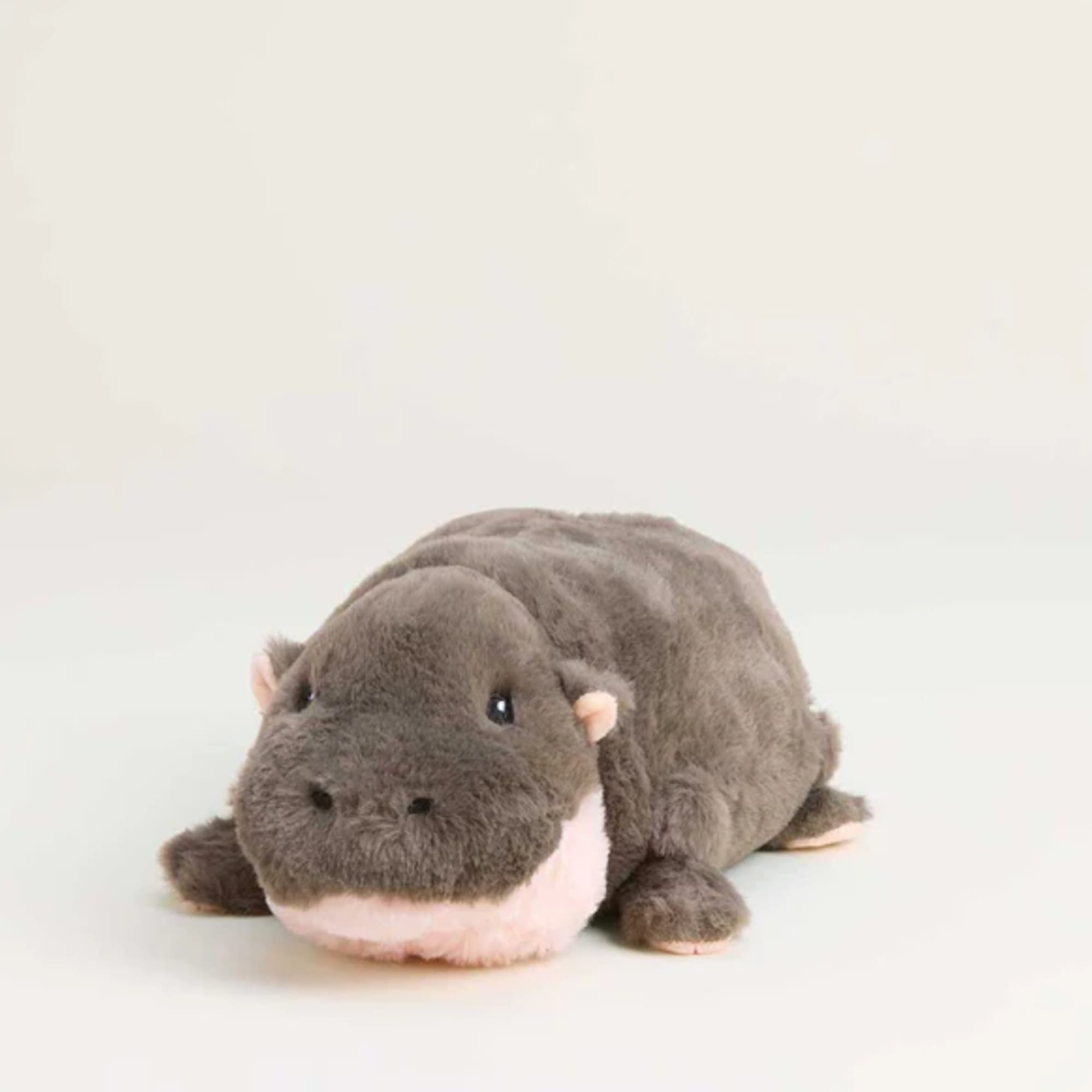 Plush hippo toy lying on a plain light background