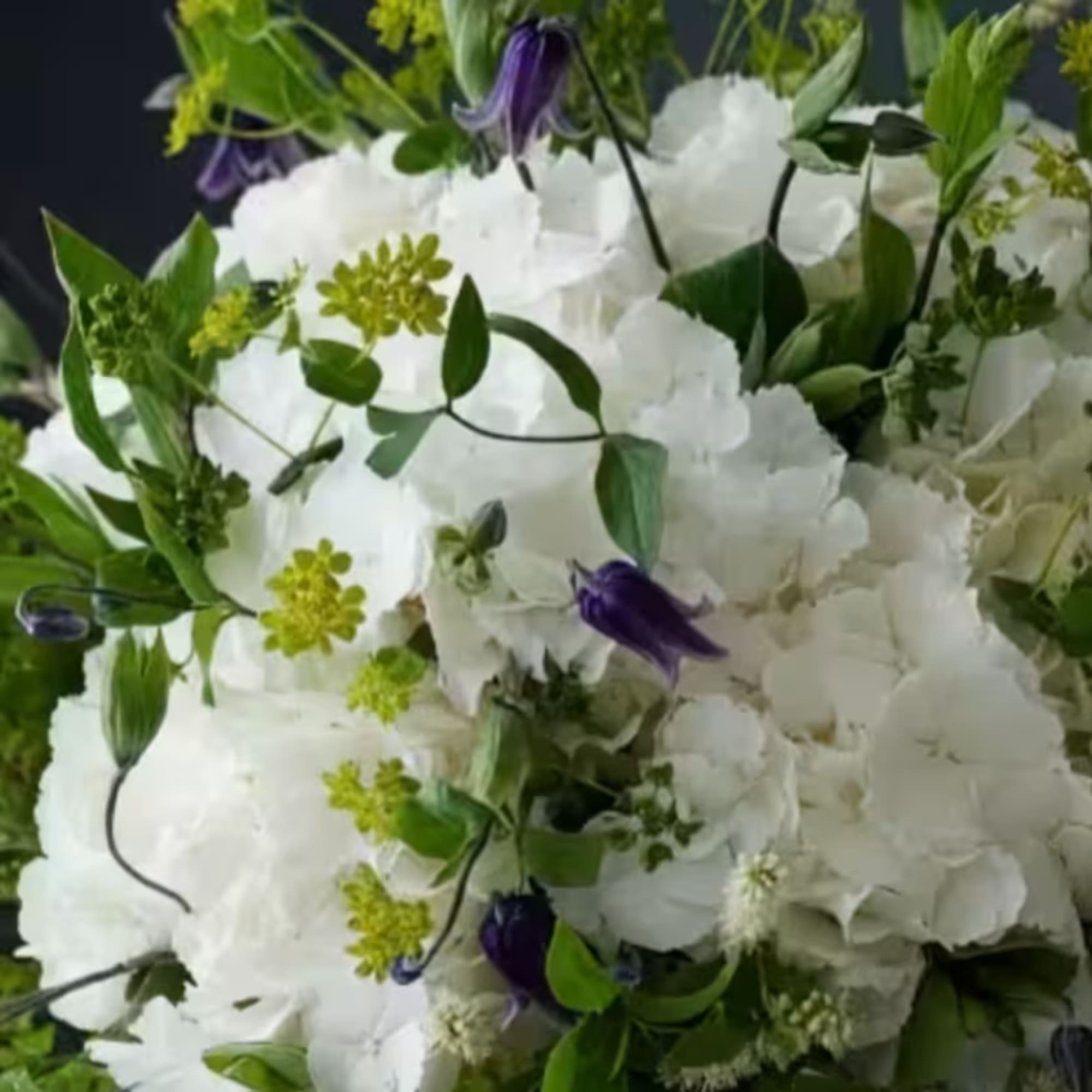 White floral bouquet with purple accents and green foliage