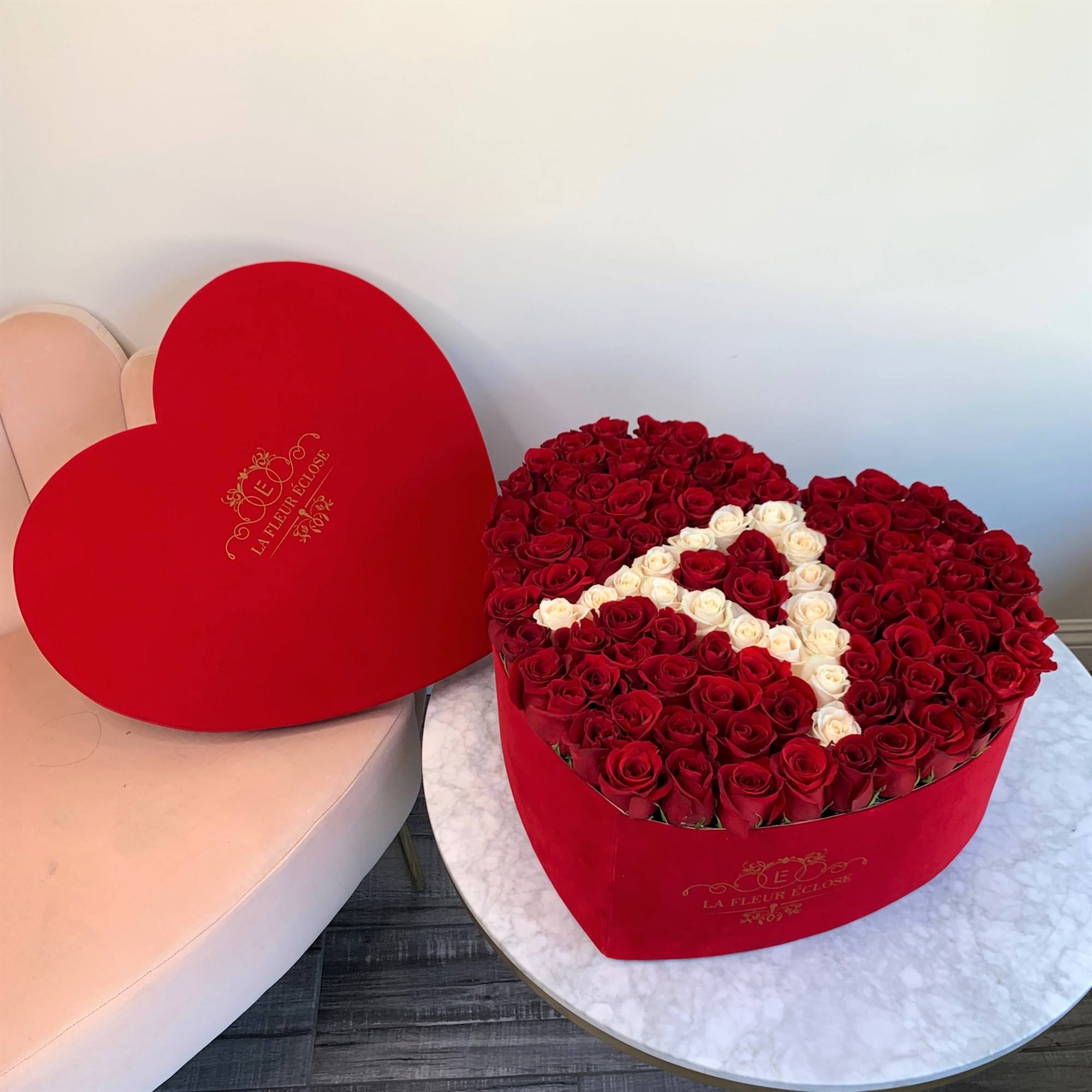 Heart-shaped box of red and white roses beside a matching heart lid