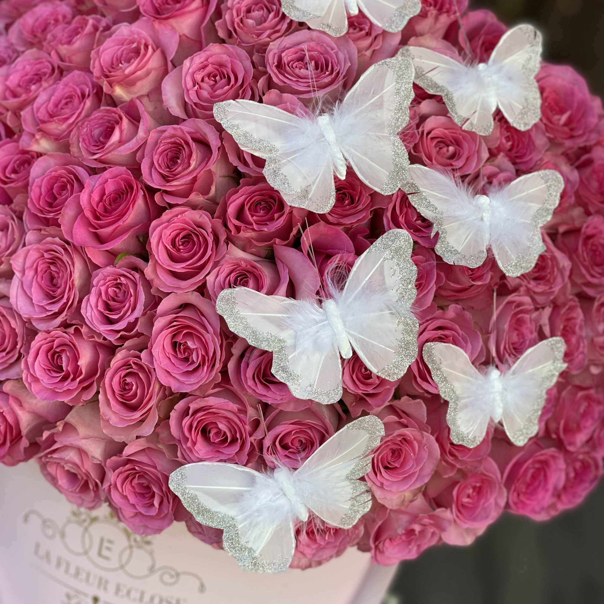 Bouquet of pink roses with white butterfly decorations in a round box