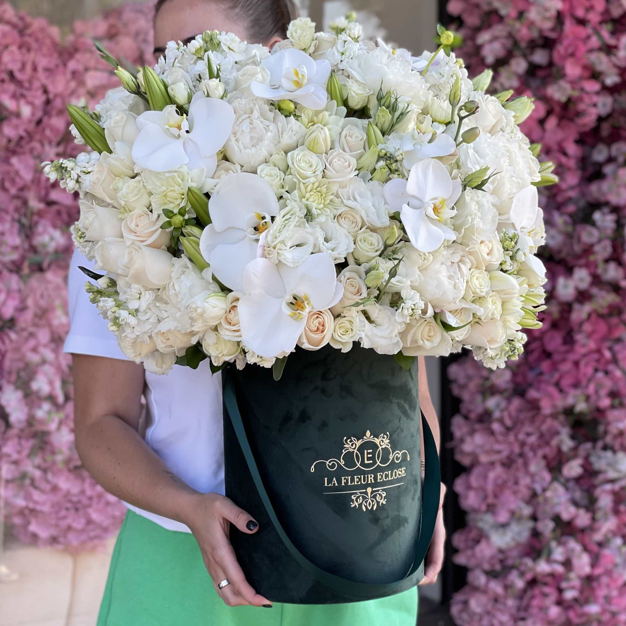 Large white bouquet with orchids and roses in a dark green box